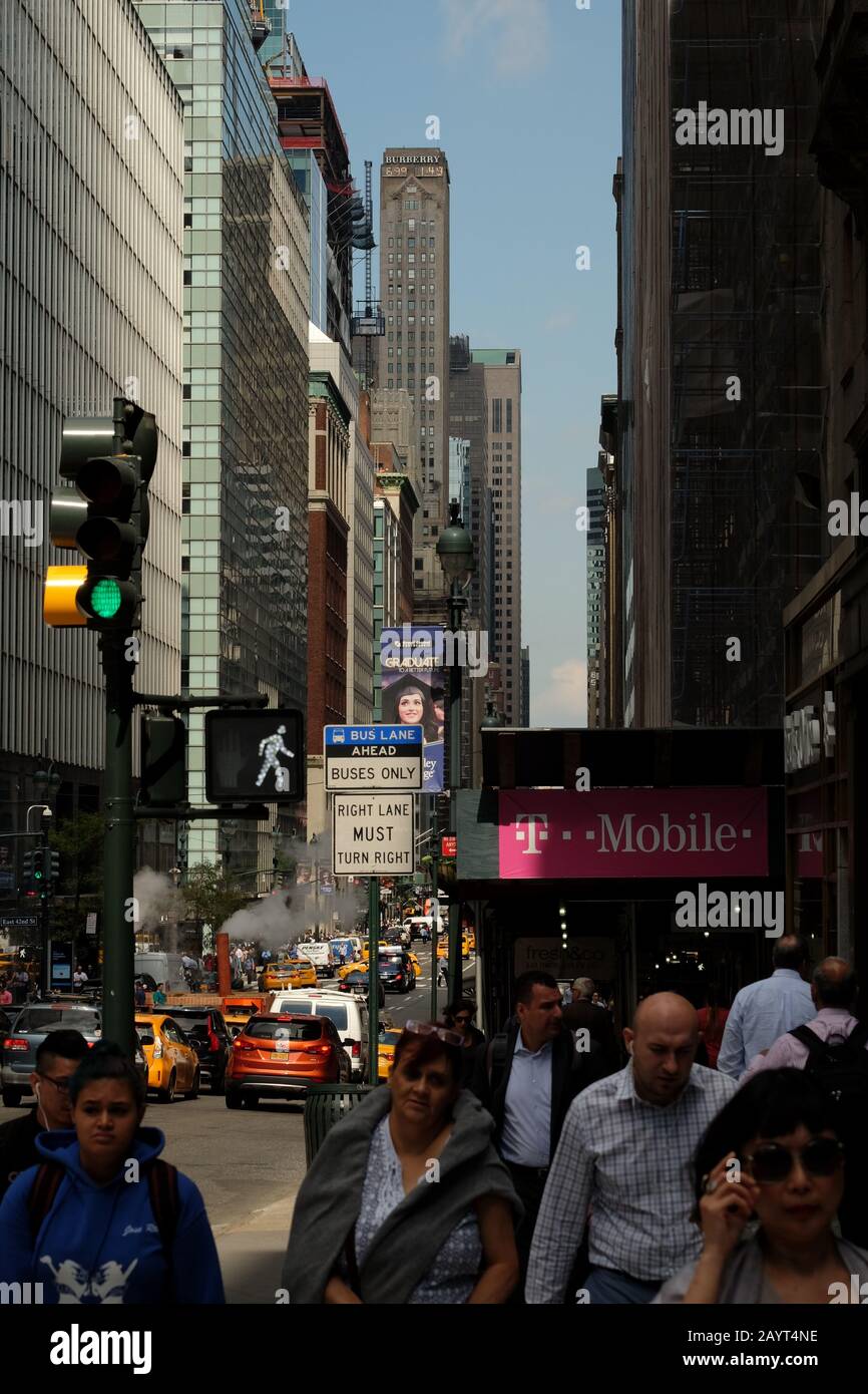 Pedoni e auto, una trafficata strada su Madison Avenue, l'alto e sottile edificio art deco Burberry più alto in un canyon di alte torri Foto Stock