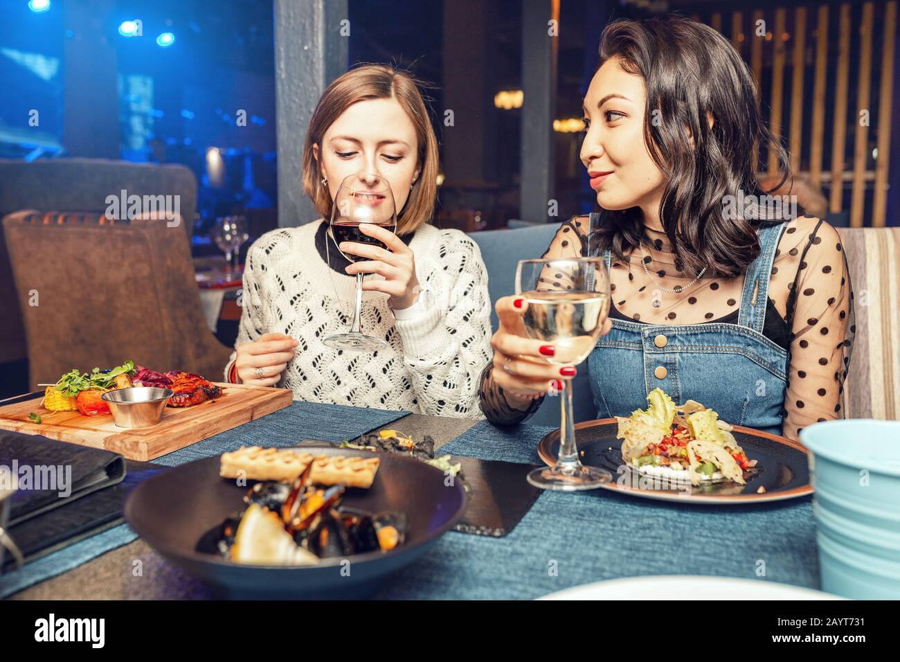 Due amici ragazze che chiacchierano e bevono vino in un ristorante in un night club. Concetto di amicizia e cibo e bevande Foto Stock