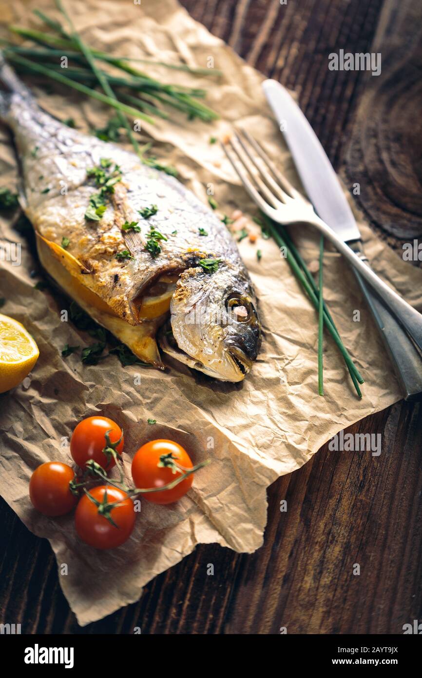 Orata al forno con limone, erba cipollina e sale. Foto Stock