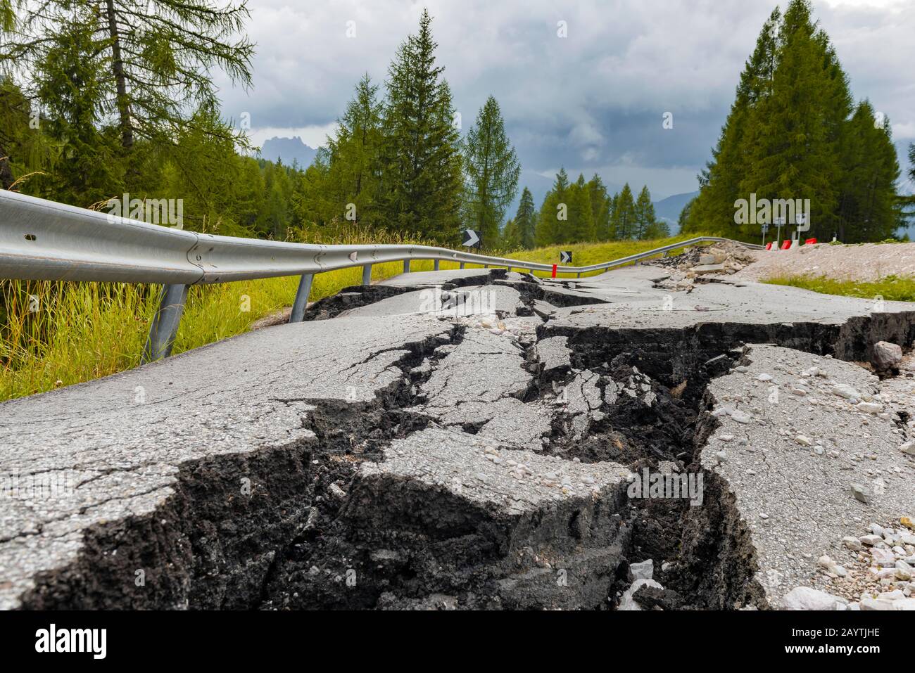 Strada spezzata con crepe nel fondo stradale, strada srotta di una strada di montagna, Belluno, Italia Foto Stock