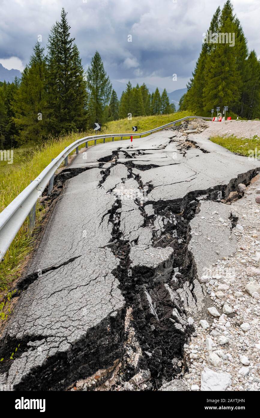 Strada spezzata con crepe nel fondo stradale, strada srotta di una strada di montagna, Belluno, Italia Foto Stock
