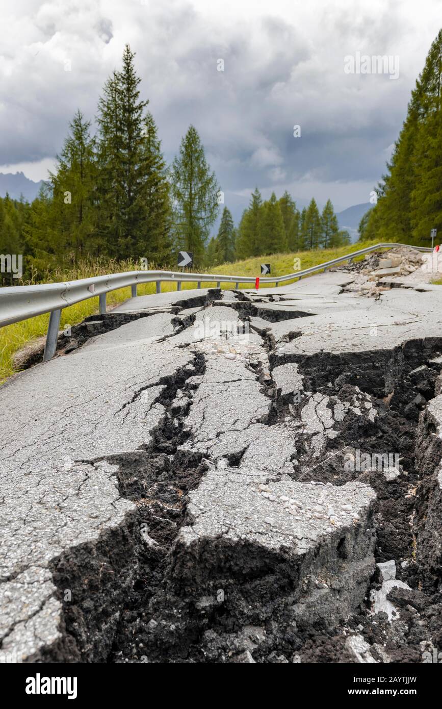 Strada spezzata con crepe nel fondo stradale, strada srotta di una strada di montagna, Belluno, Italia Foto Stock