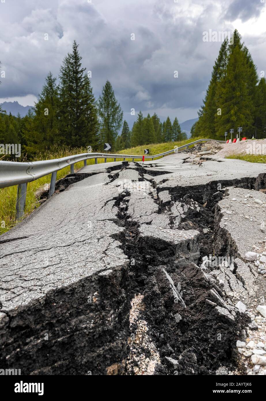 Strada spezzata con crepe nel fondo stradale, strada srotta di una strada di montagna, Belluno, Italia Foto Stock