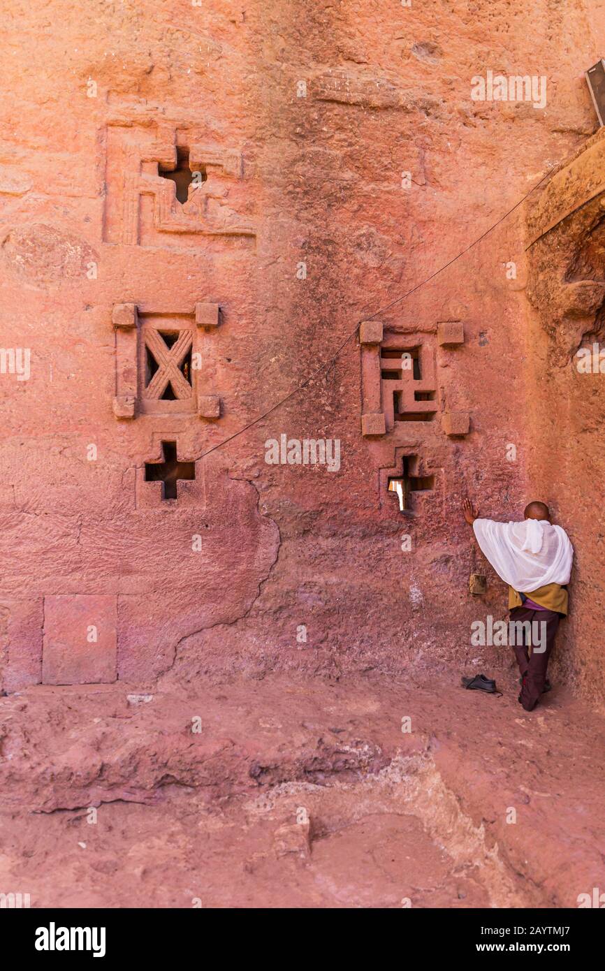 Pellegrino che prega al muro della chiesa di Bete Medhane Alem in Lalibela Etiopia Foto Stock