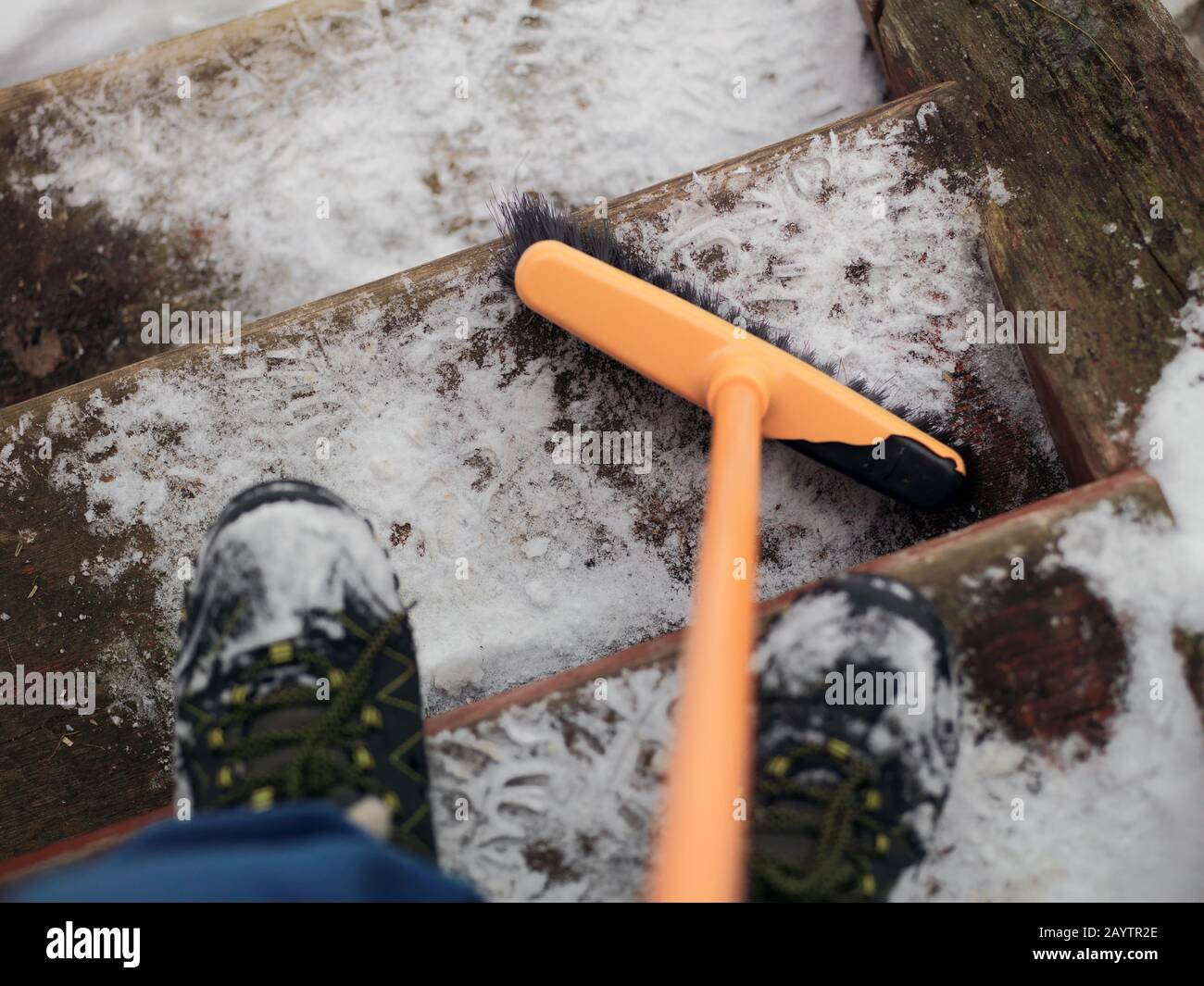 Colpo di testa di un uomo che rimuove la neve dai gradini di legno Foto Stock