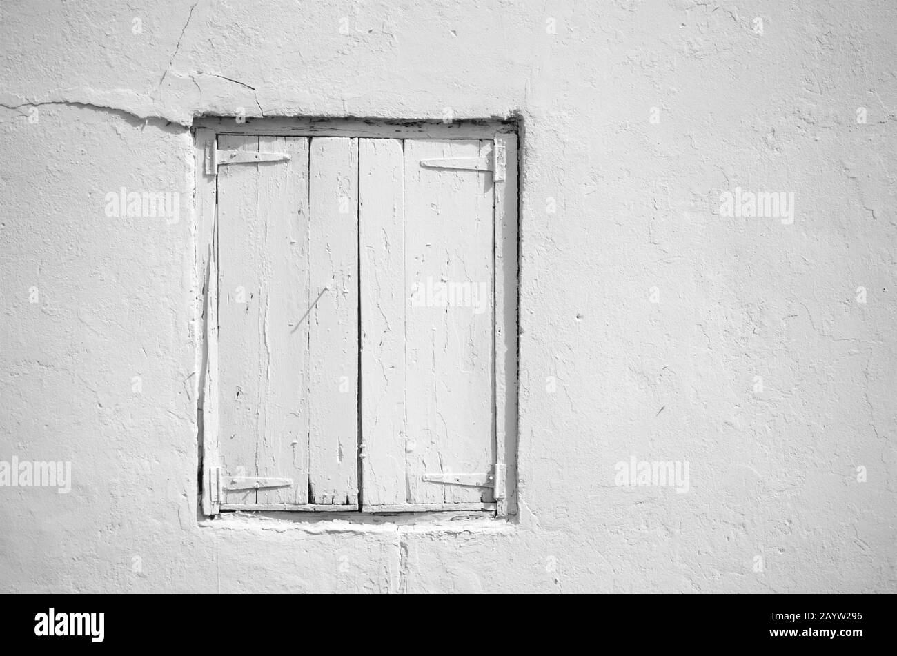 Vista dal taglio corto di un edificio in cemento dipinto di bianco con persiane di legno chiuse di bianco. Fotografia in bianco e nero. Foto Stock