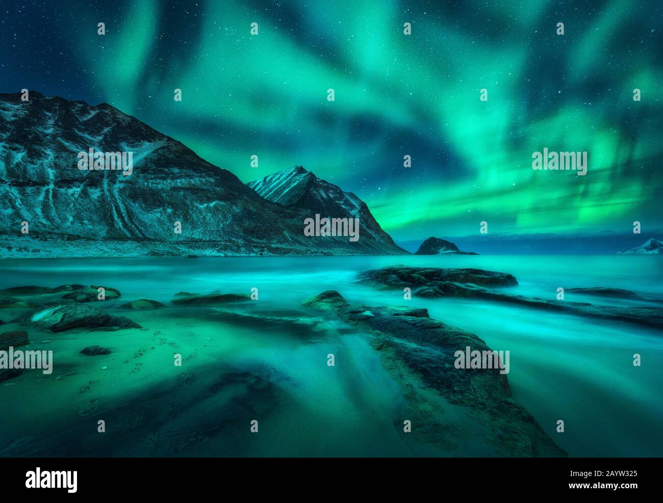 Aurora borealis su montagne innevate, costa del mare con spiaggia sabbiosa Foto Stock