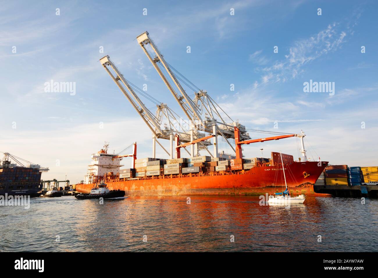 Uno yacht passa la nave Da Container "Cap Palliser" che scarica al porto di Oakland. San Francisco California, Stati Uniti Foto Stock