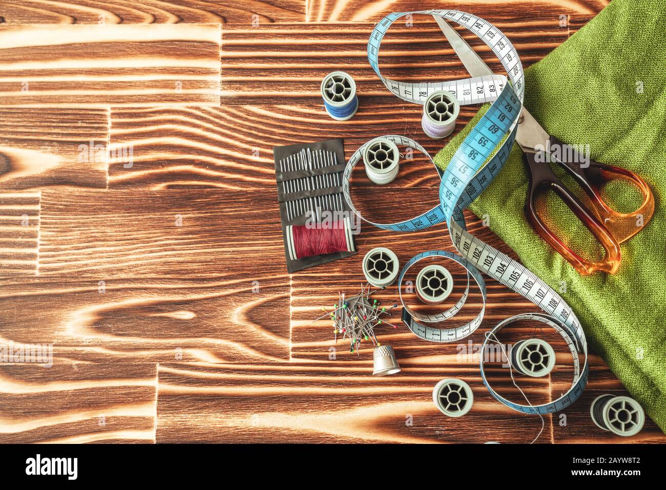 Gruppo di oggetti sulle apparecchiature per cucire impostato su uno sfondo di legno. Concetto di cucito e di sartoria Foto Stock
