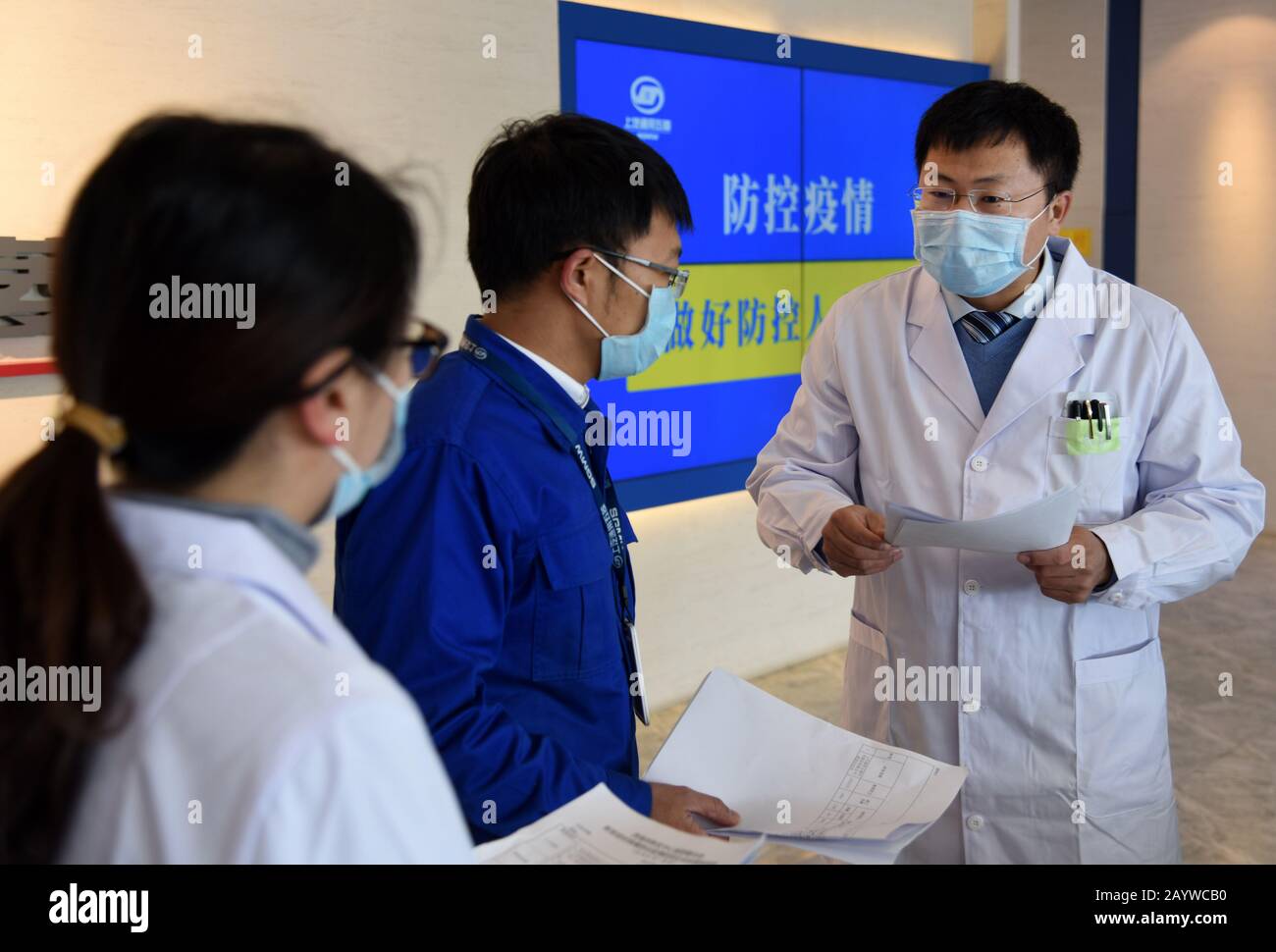 (200217) -- QINGDAO, 17 febbraio 2020 (Xinhua) -- un medico (R) comunica con i membri del personale del lavoro di prevenzione e controllo dell'epidemia alla base del costruttore di automobili SGMW a Qingdao, nella provincia cinese orientale dello Shandong, 17 febbraio 2020. Per garantire la normale produzione di imprese dopo aver ripreso il lavoro, Xihai'an (West Coast) New Area di Qingdao ha istituito team di assistenza medica per servire le imprese. Il primo lotto di 279 personale medico di 50 team di assistenza medica è stato posizionato in aziende chiave per assistere nella prevenzione e nel controllo dell'epidemia. (Xinhua/Li Ziheng) Foto Stock