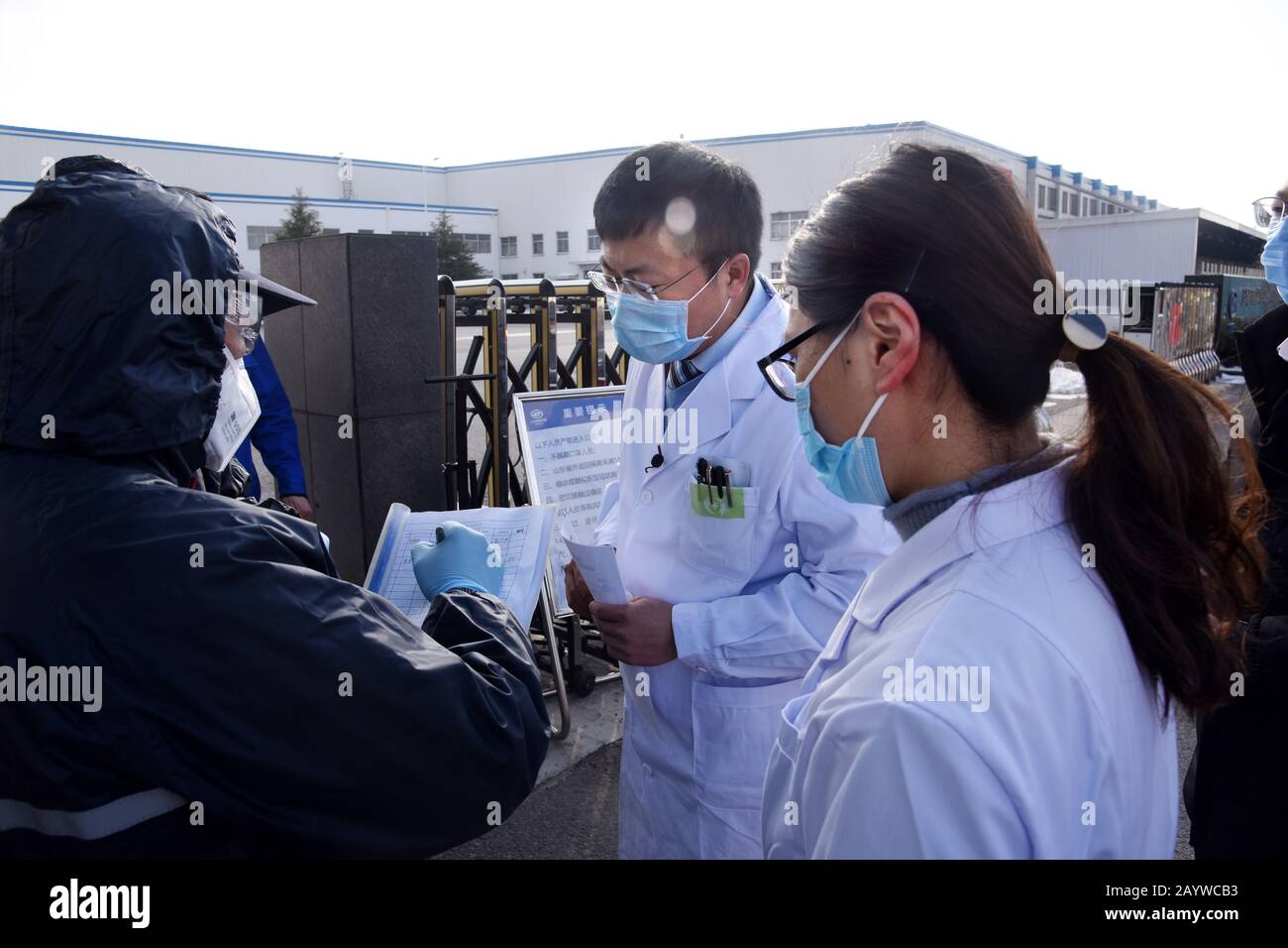 (200217) -- QINGDAO, 17 febbraio 2020 (Xinhua) -- un team di assistenza medica controlla un record della temperatura corporea dei lavoratori alla base del costruttore di automobili SGMW a Qingdao, nella provincia cinese orientale dello Shandong, 17 febbraio 2020. Per garantire la normale produzione di imprese dopo aver ripreso il lavoro, Xihai'an (West Coast) New Area di Qingdao ha istituito team di assistenza medica per servire le imprese. Il primo lotto di 279 personale medico di 50 team di assistenza medica è stato posizionato in aziende chiave per assistere nella prevenzione e nel controllo dell'epidemia. (Xinhua/Li Ziheng) Foto Stock