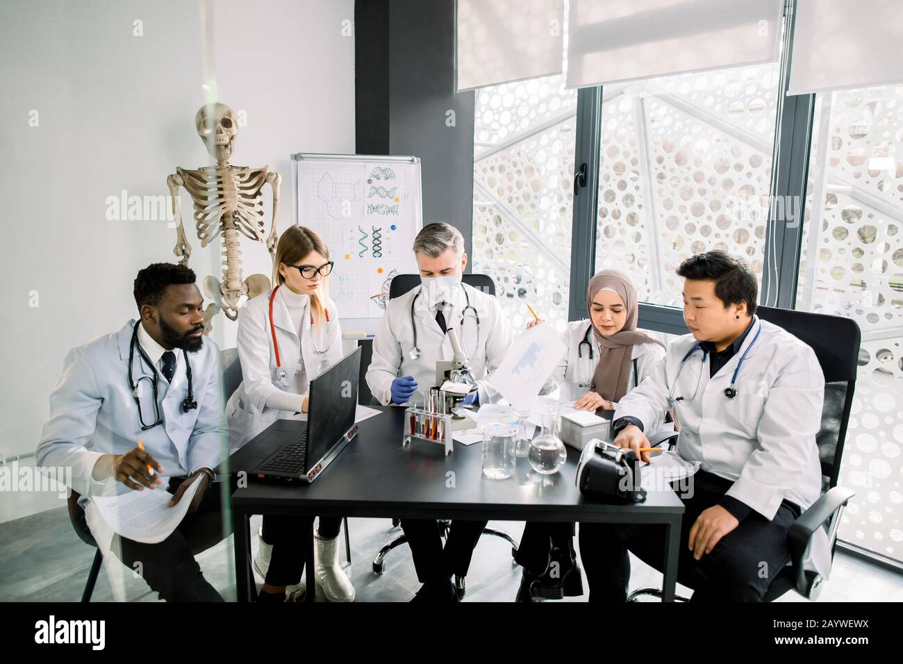 Gruppo di scienziati multietnici e Senior maschili Supervisor che lavorano con microscopi e provette in un moderno laboratorio di ricerca scientifica. Biochimica Foto Stock