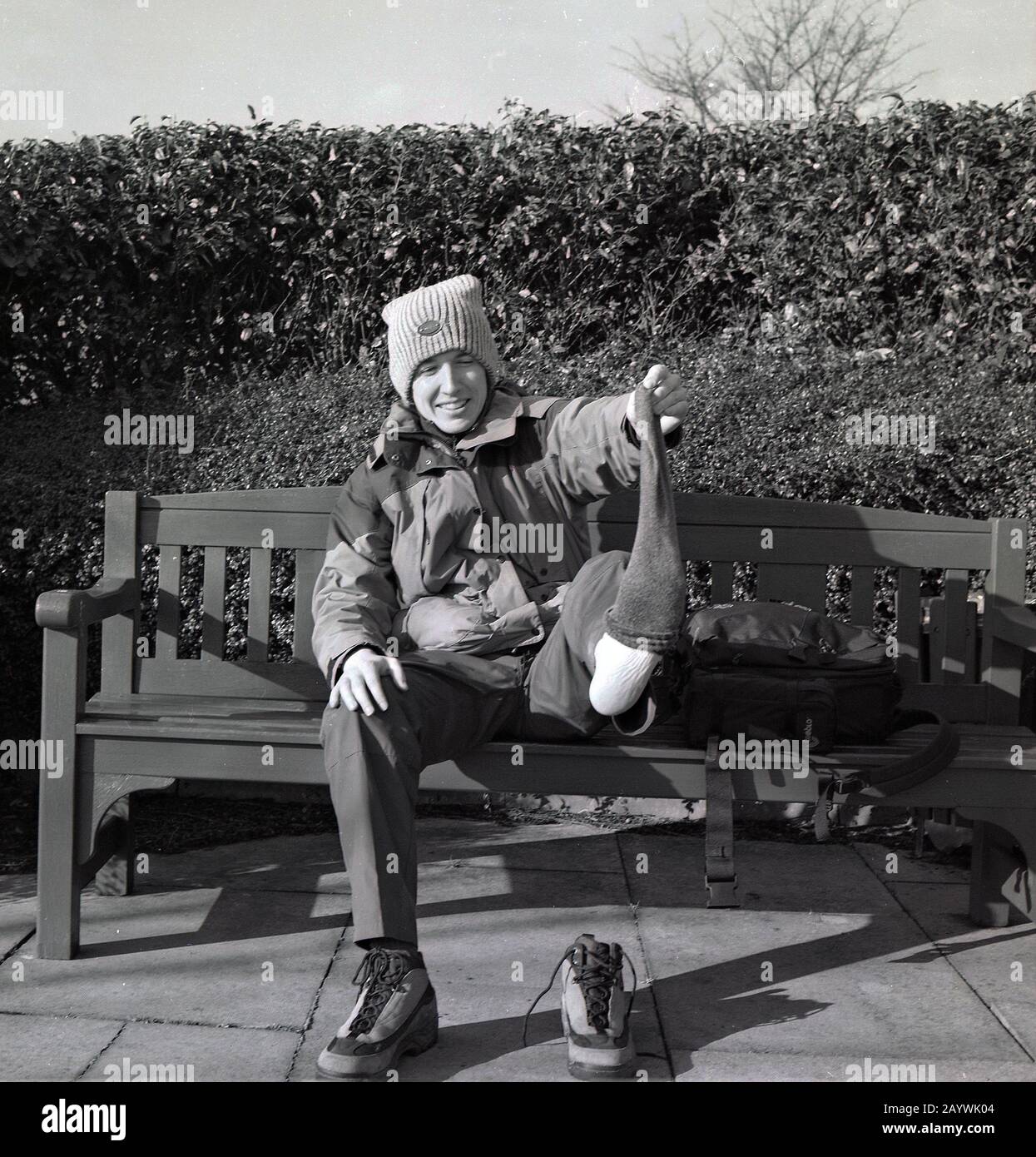 1980s, escursionista adulto seduto su una panchina che mostra il suo calzino, Scozia. Foto Stock