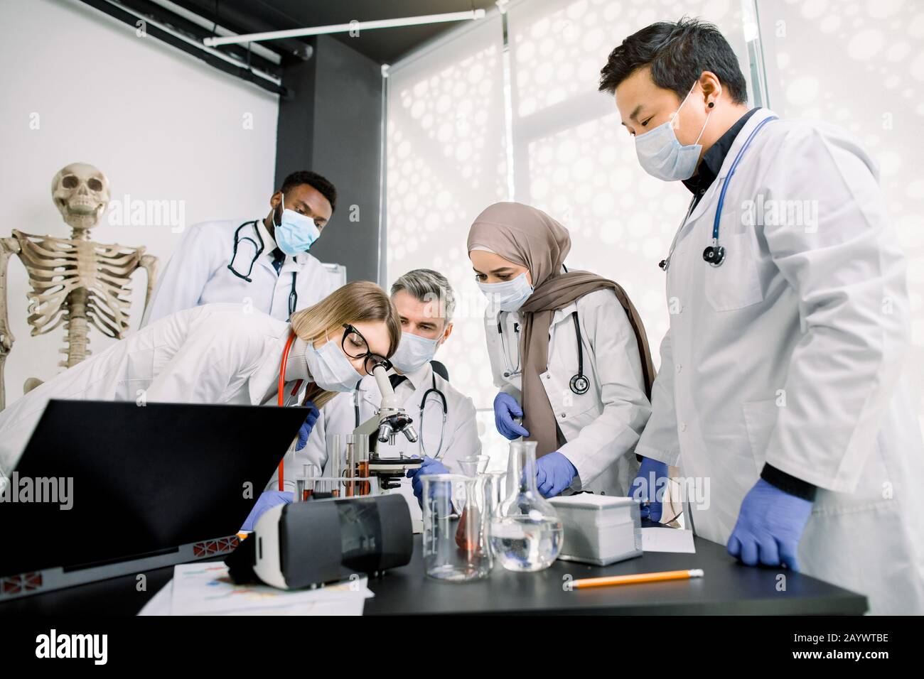 Team di operatori di laboratorio, veterinari, bio-chimici che esaminano tessuti o campioni di sangue utilizzando il microscopio. Gruppo di scietisti multietniche con cui lavorare Foto Stock
