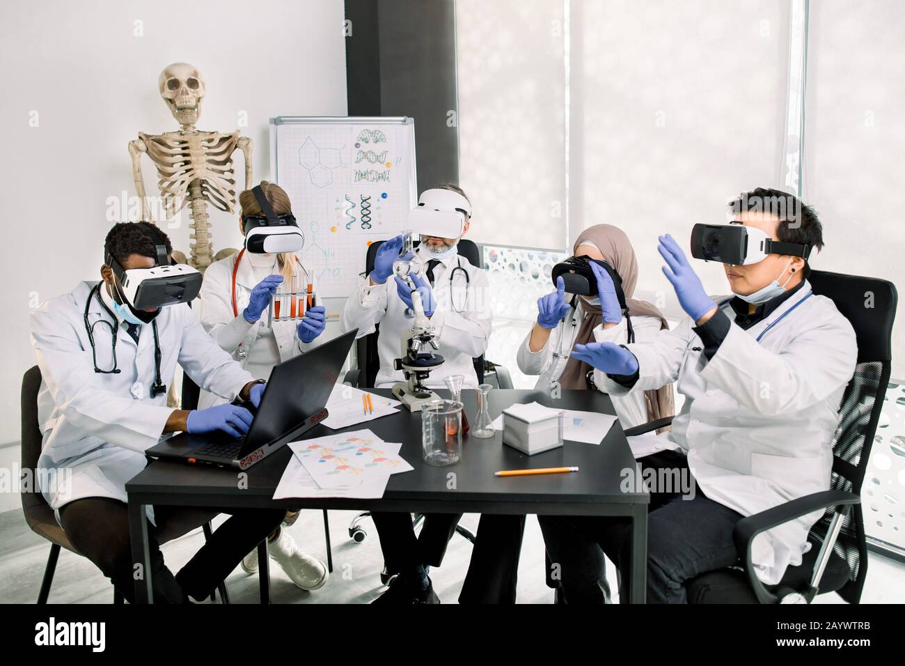 Team di medici multietnici, chimici, scienziati in moderno laboratorio di ricerca utilizzando occhiali di realtà virtuale, gesturing, toccando realtà virtuale Foto Stock
