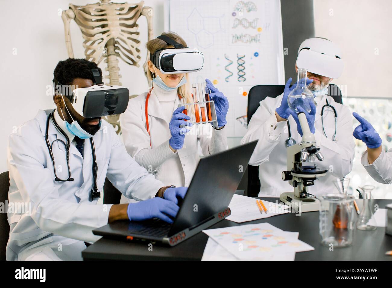 Giovani medici multietnici, farmacisti che usano occhiali di realtà virtuale in test sperimentali di nuovi farmaci, vaccini o sostanze. Donna contiene tubi con Foto Stock
