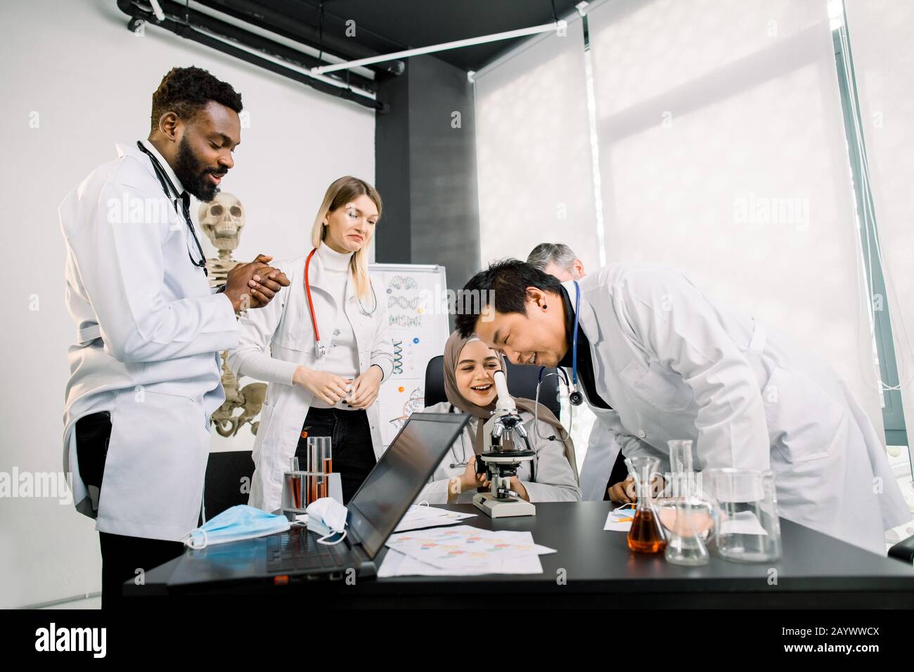 Gruppo di scienziati multietnici si sentono felici dopo il test sperimentale scientifico di successo, la nuova scoperta, la soluzione. L'uomo asiatico sta guardando dentro Foto Stock