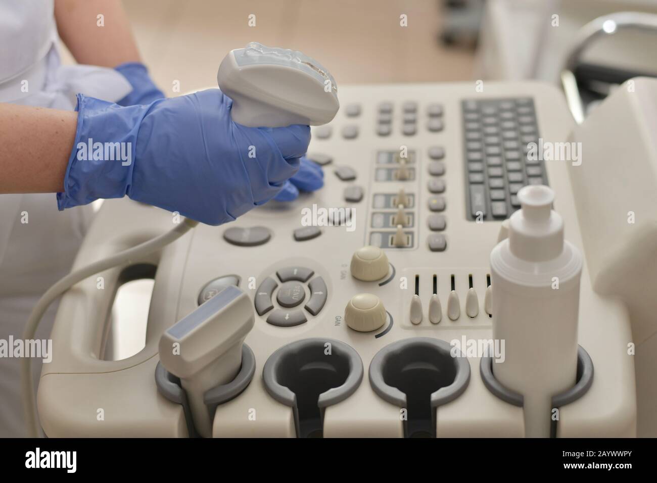 Trasduttore a ultrasuoni con gel in mano, sullo sfondo del pannello di controllo, esattamente in vista laterale. Foto Stock