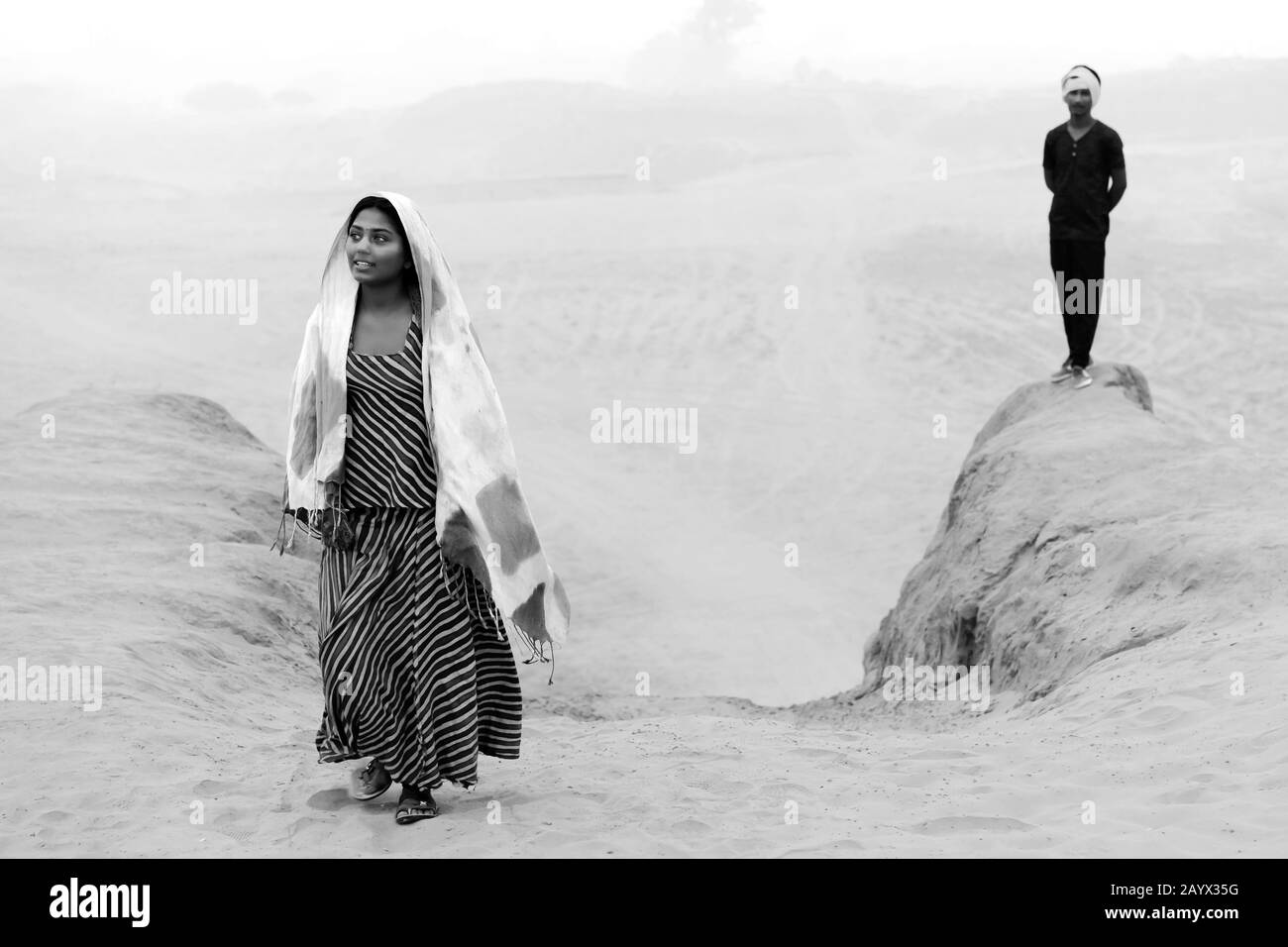 Giovane donna zingara in abiti tradizionali colorati e sorridente camminare nel deserto Thar vicino Pushkar, Rajasthan, India. Foto Stock