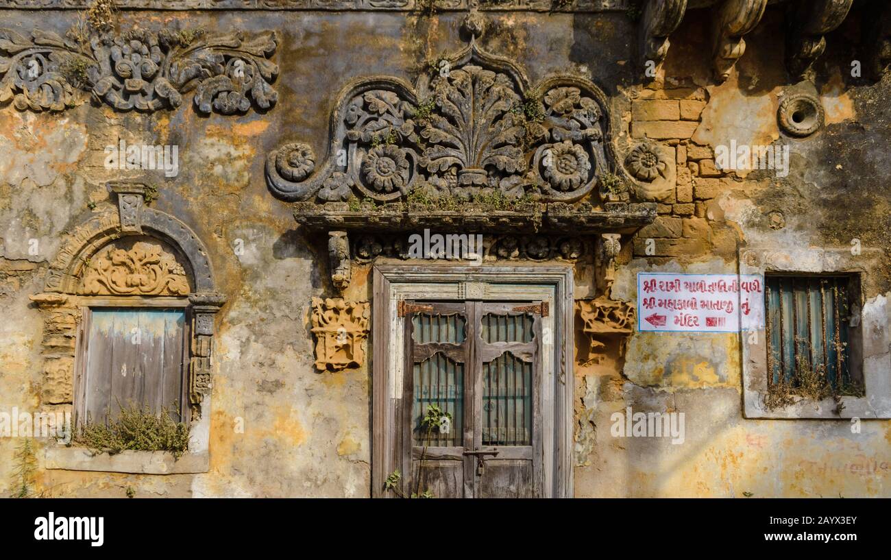 Il dettaglio ornato su una bella porta sbiadita, pareti in mattoni e la facciata di un antico tempio a Diu. Foto Stock