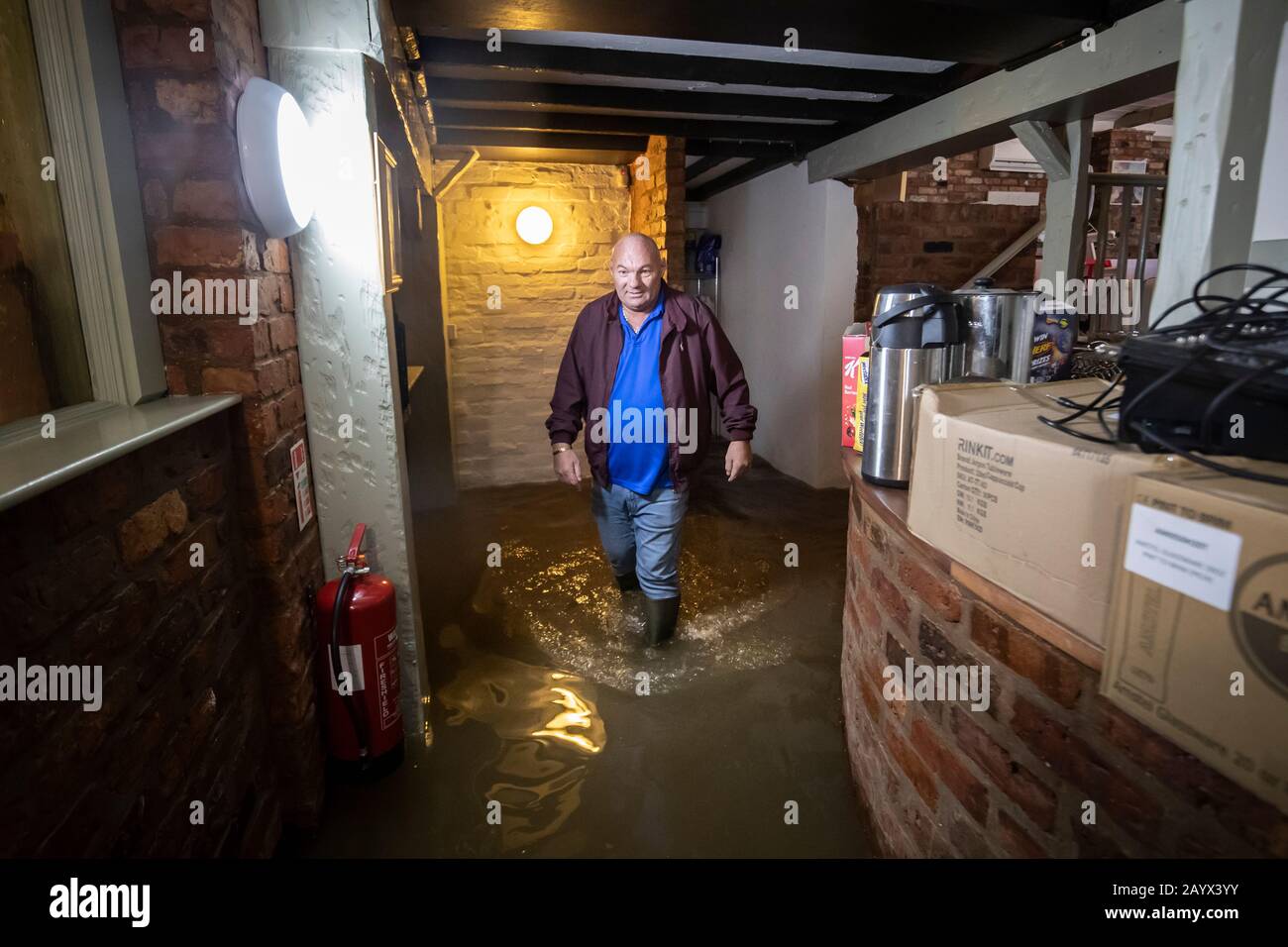 Il Locatore Colin Reynolds cammina attraverso l'acqua alluvionale nella locanda delle navi di Acaster Malbis, vicino York, dopo la tempesta Dennis. Foto Stock