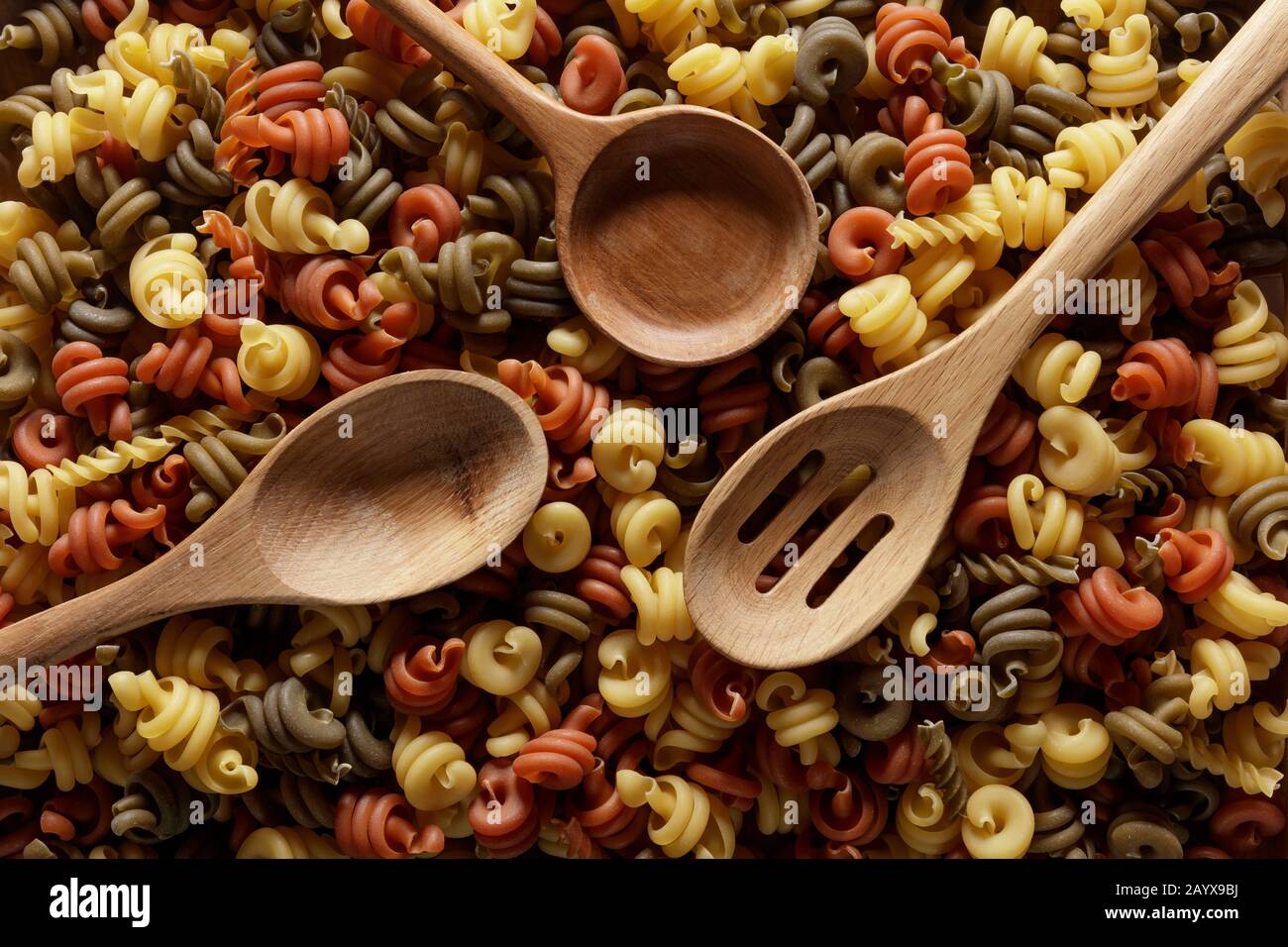 Tre cucchiai di legno su un letto di pasta secca Foto Stock