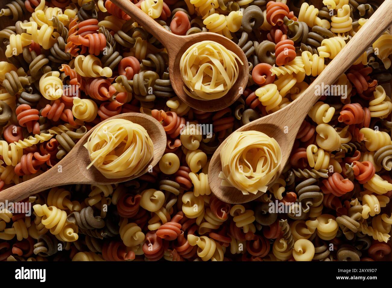 Tre cucchiai di legno su un letto di pasta secca Foto Stock