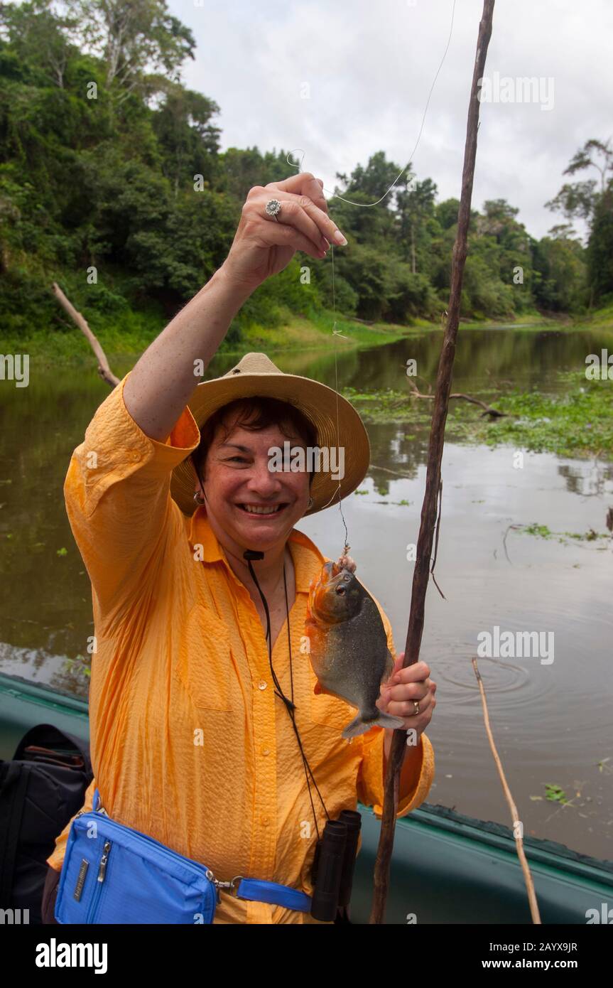 Una donna con un Piranha su un piccolo fiume nella Riserva nazionale Pacaya-Samiria lungo il fiume Ucayali nel bacino peruviano del fiume Amazzonia vicino a Iquitos Foto Stock