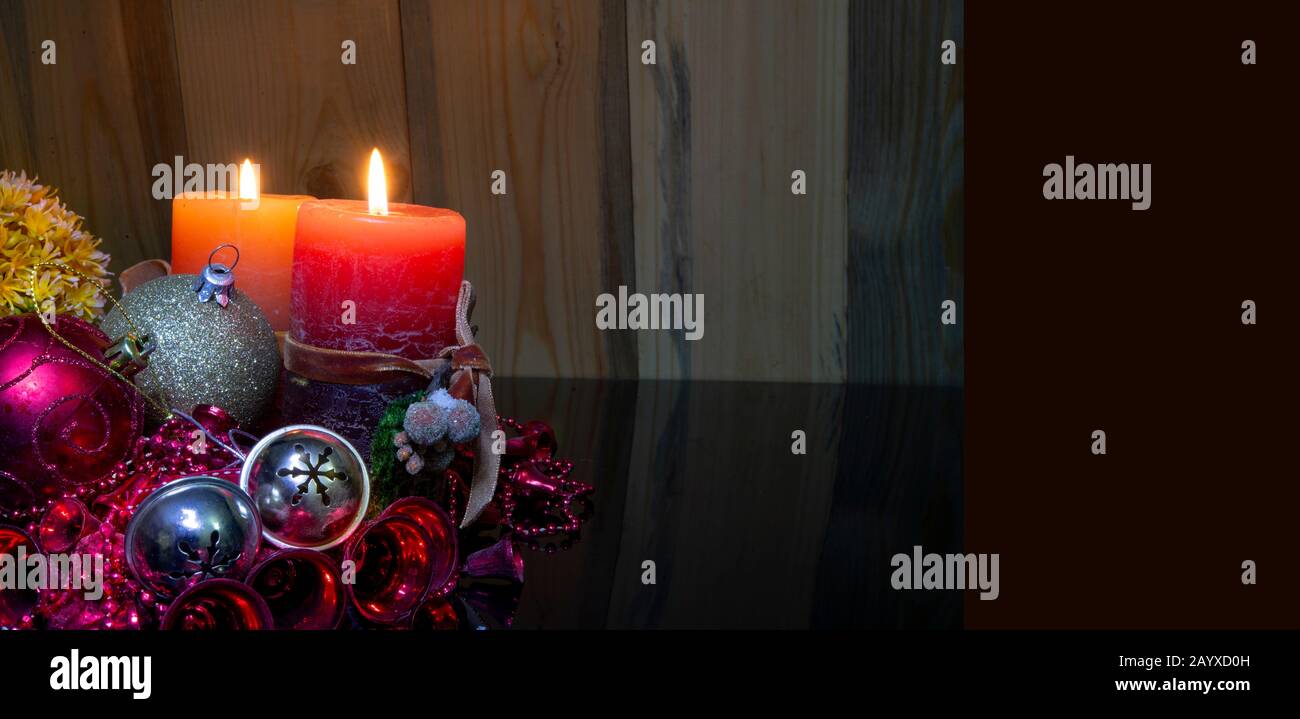 Banner di concetto di Natale con due candele rosse che si illuminano su sfondo di legno Foto Stock
