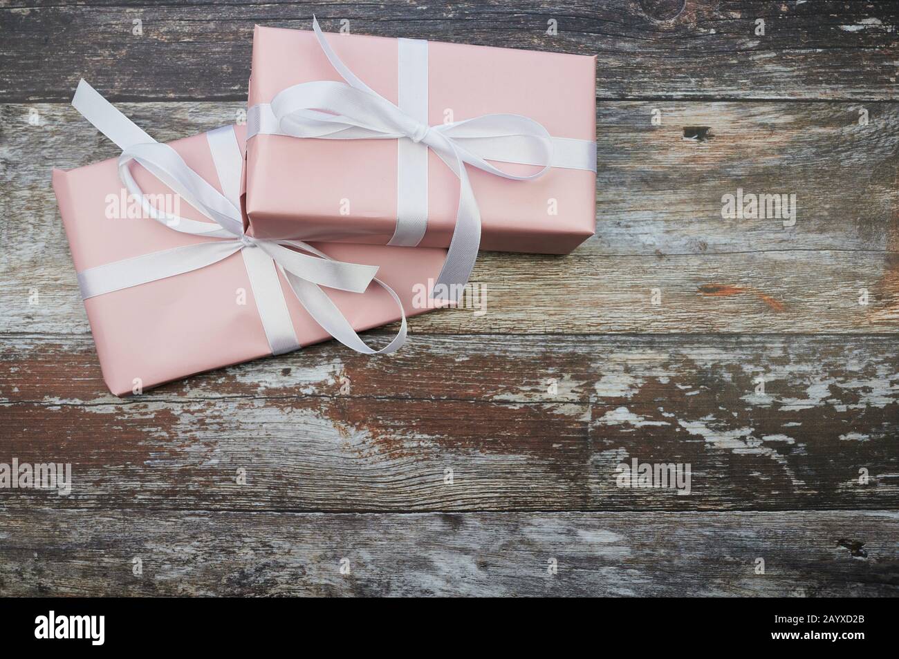 due regali rosa nell'angolo sinistro su sfondo marrone in legno con spazio copia Foto Stock