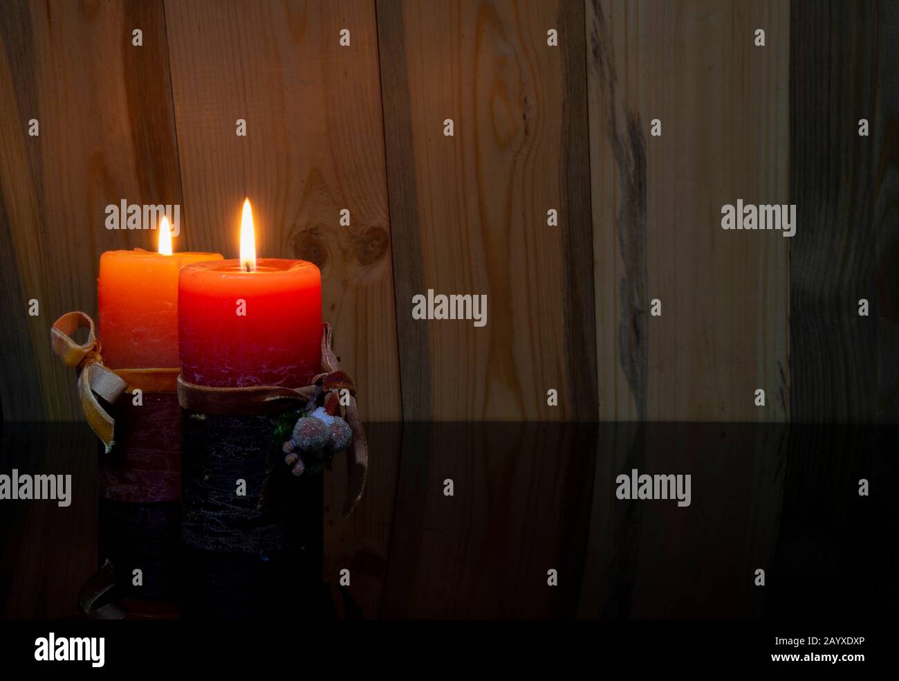 Banner di concetto di Natale con due candele rosse che si illuminano su sfondo di legno Foto Stock