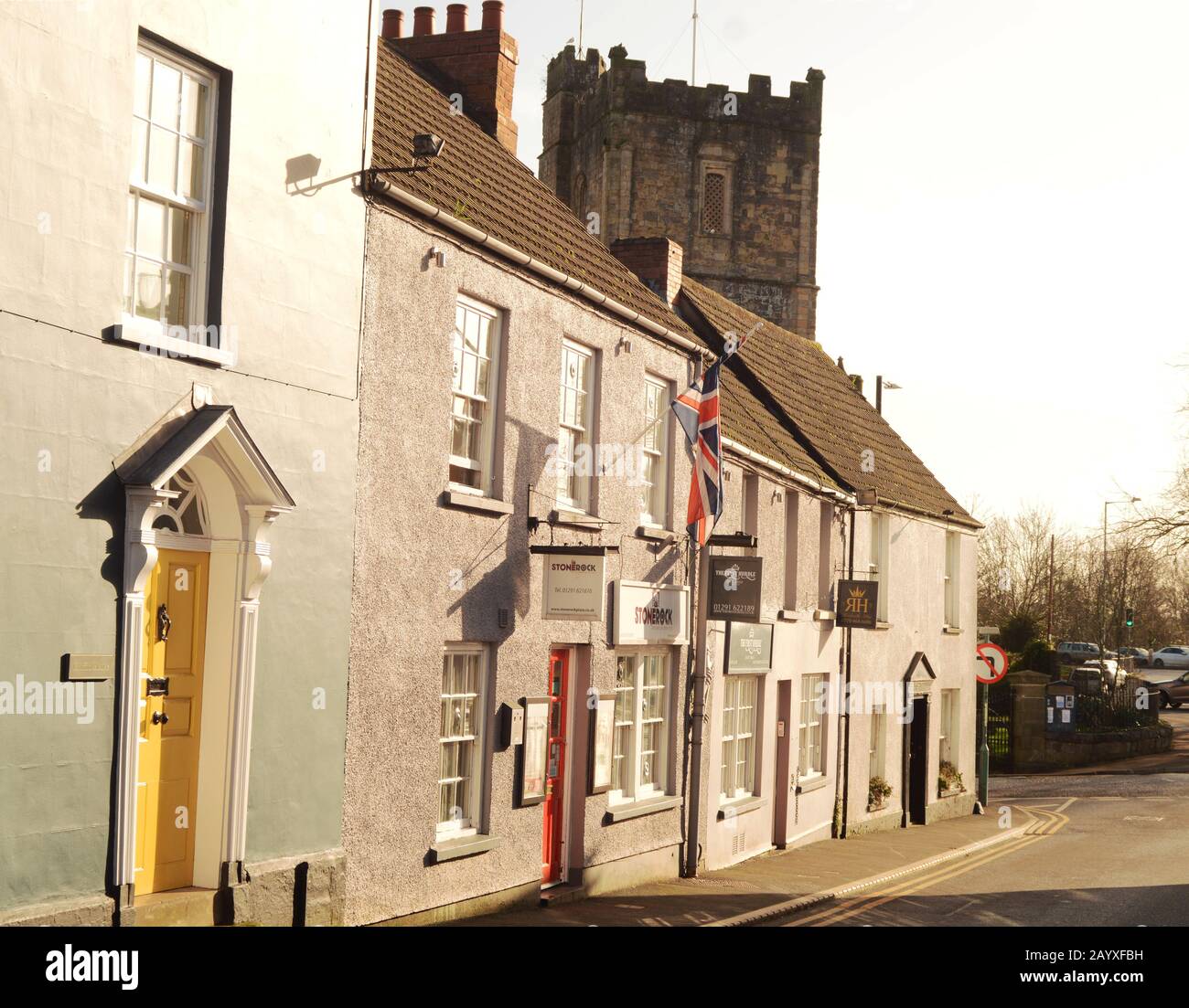 Una vista delle Case e delle piccole imprese lungo Upper Church Street a Chepstow, nel Galles del Sud, con la Chiesa del Priorato di St Mary che piange sui tetti Foto Stock