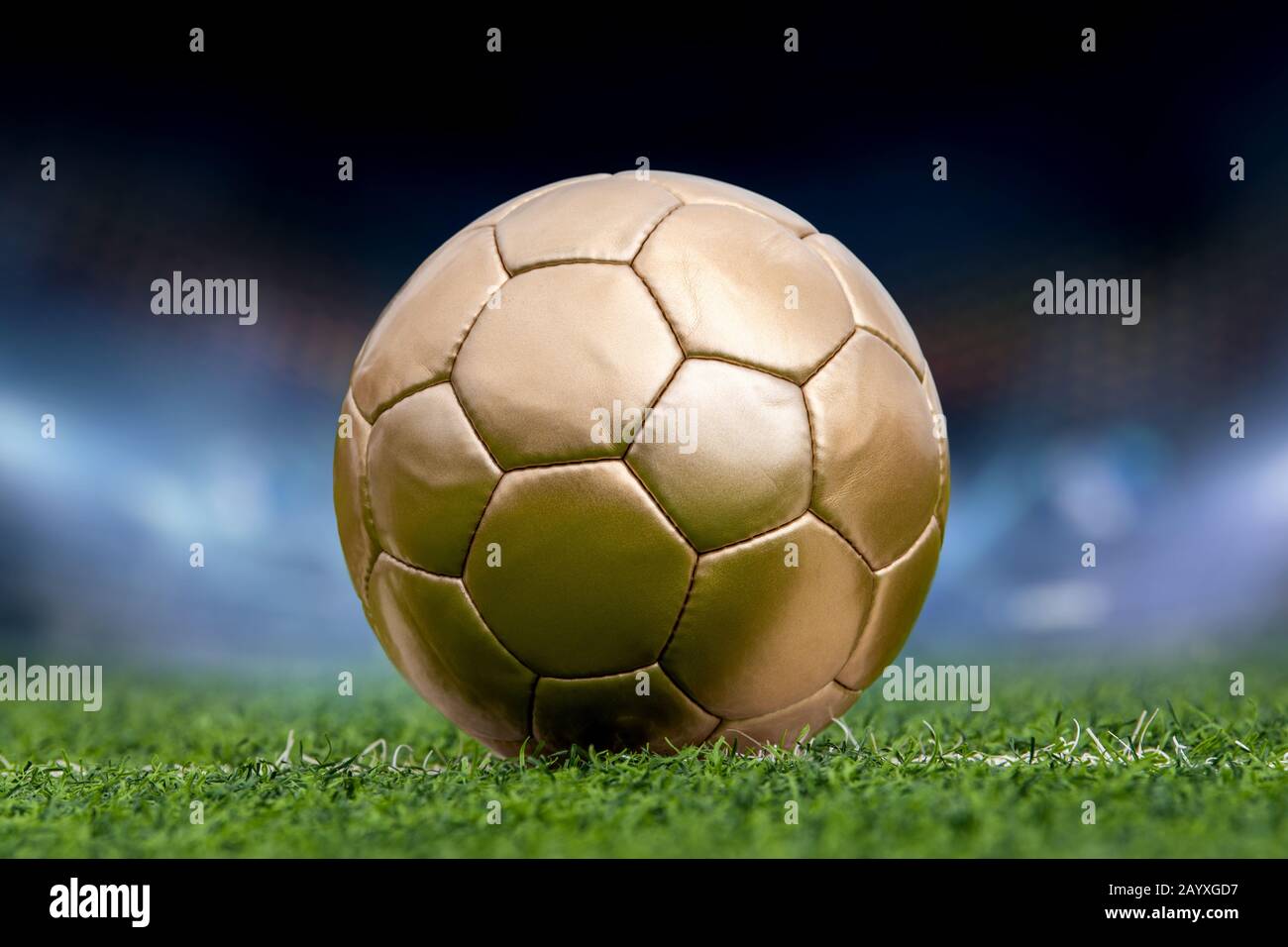 Closeup palla di calcio d'oro e stadio con i tifosi la notte Foto Stock