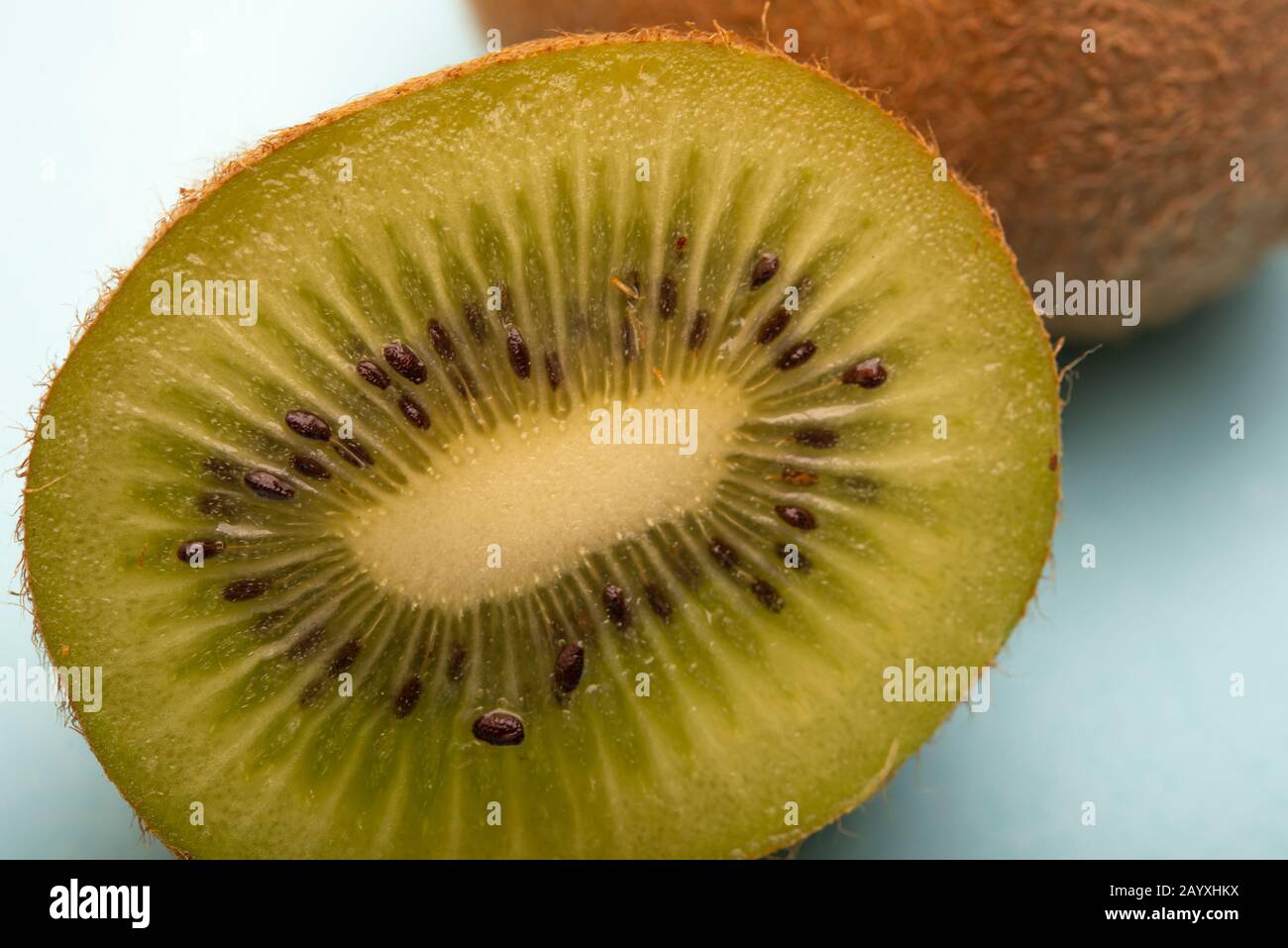 Frutta Kiwi isolata a metà tagliata su sfondo blu Foto Stock
