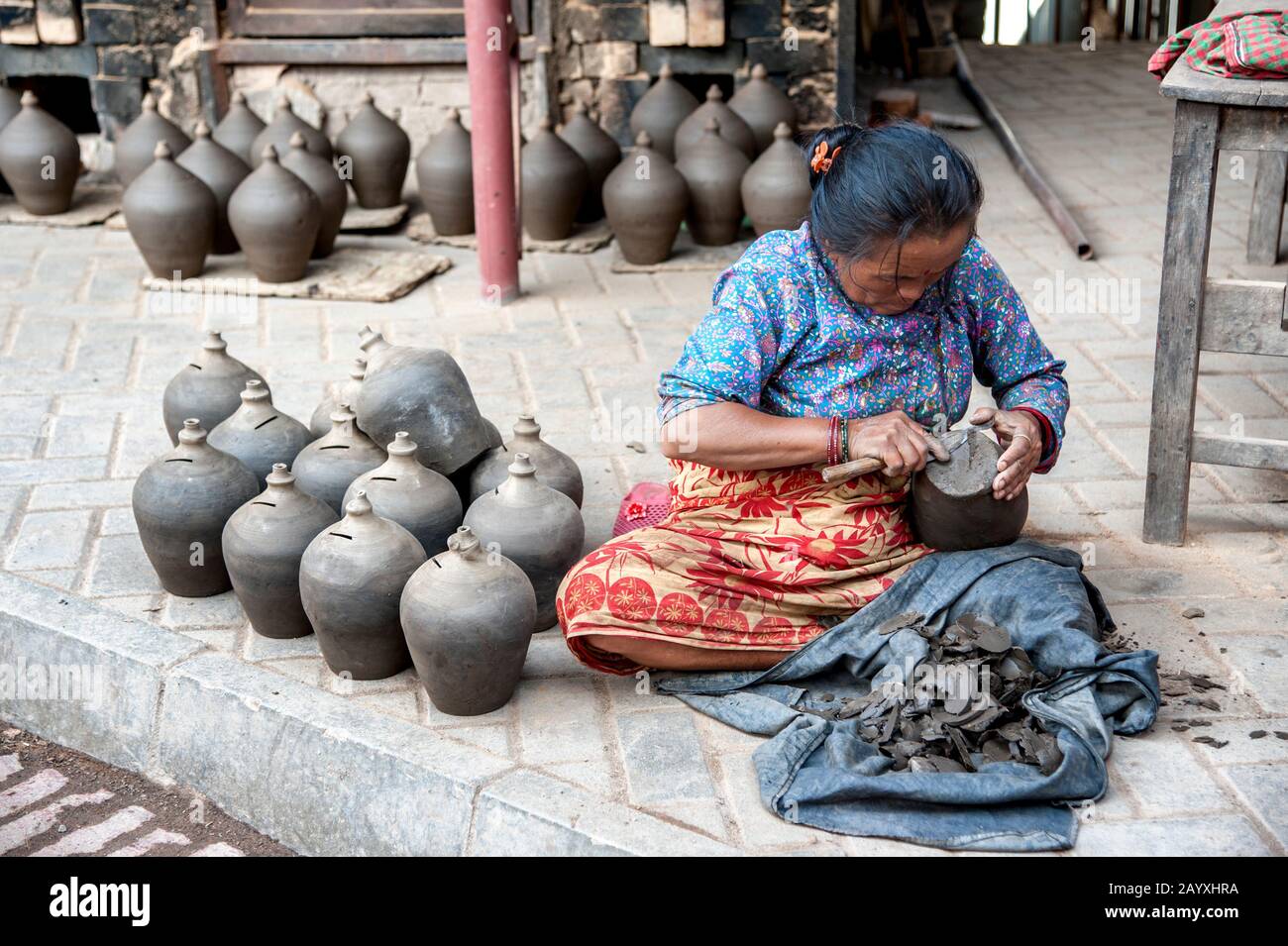 Donna nepalese che fa la ceramica in piazza della ceramica, una piazza pubblica piena di ruote di ceramica e file di vasi di argilla - Bhaktapur Nepal Foto Stock