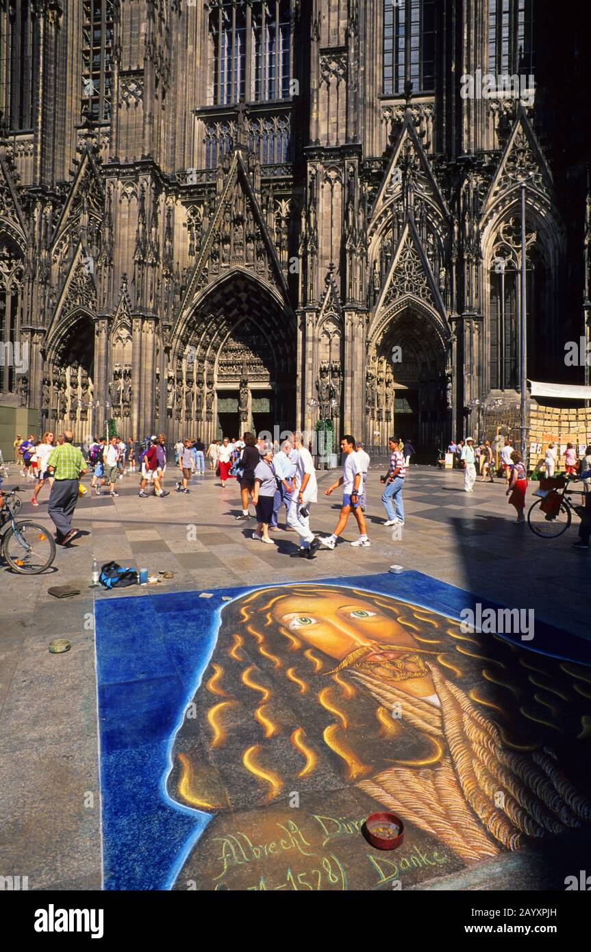 Un artista del marciapiede sta creando un dipinto di gesso di fronte alla cattedrale di Colonia nel Nordrhein-Westfalen, in Germania. Foto Stock