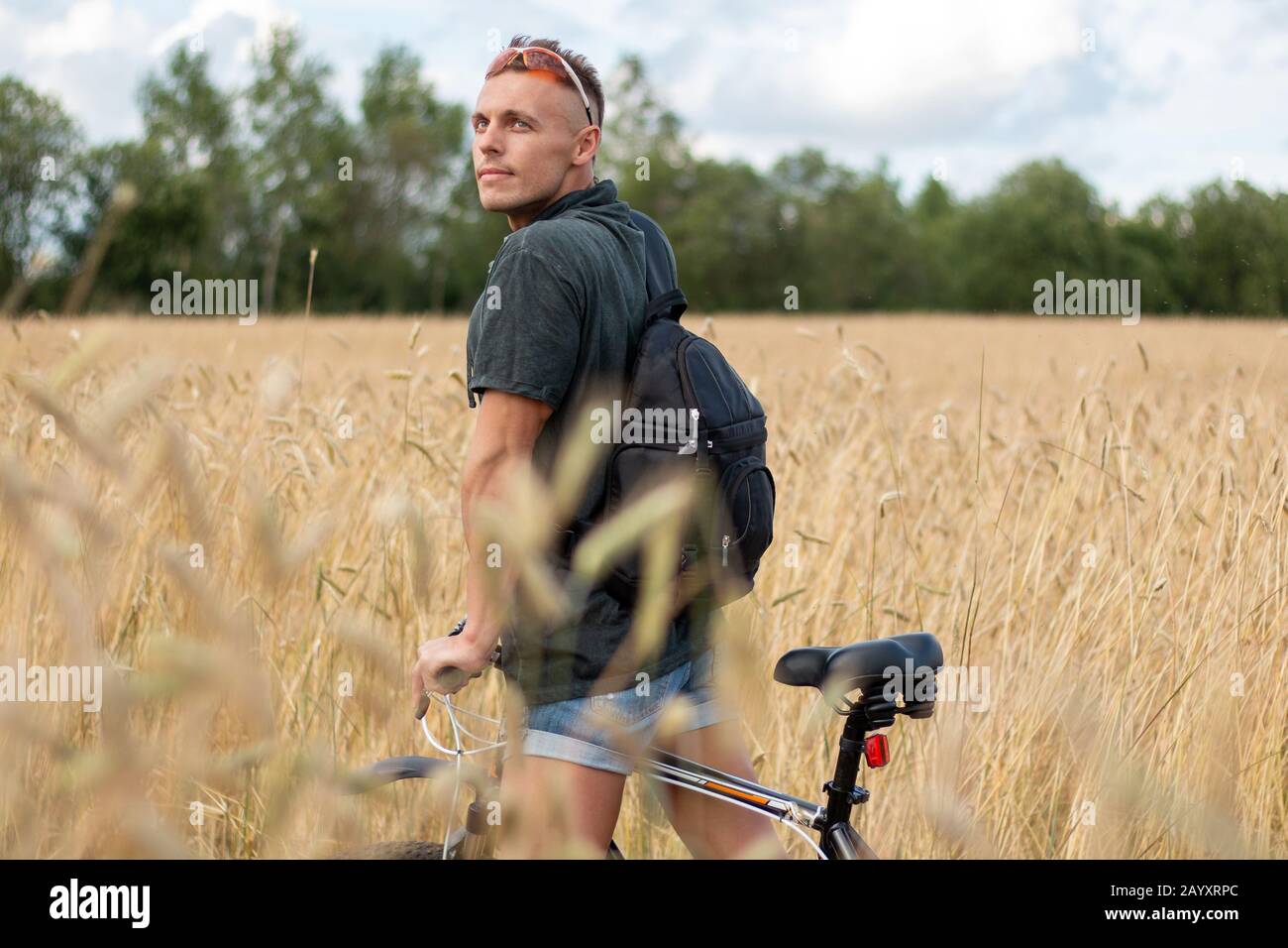 Un uomo in un campo su una bicicletta. Sullo sfondo del cielo. Foto Stock