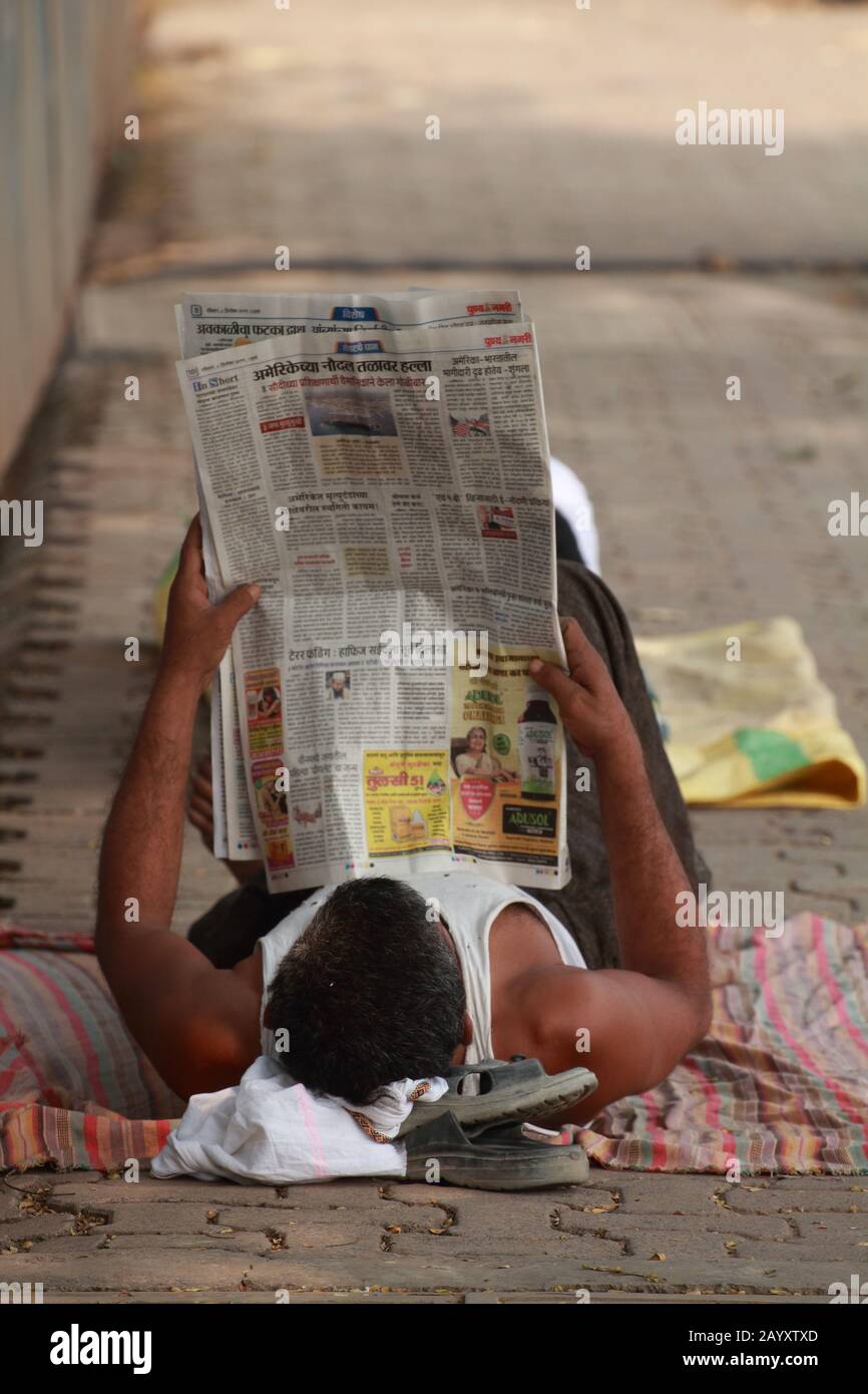 L'uomo sdraiato sul suo letto e godendo della lettura delle notizie Foto Stock