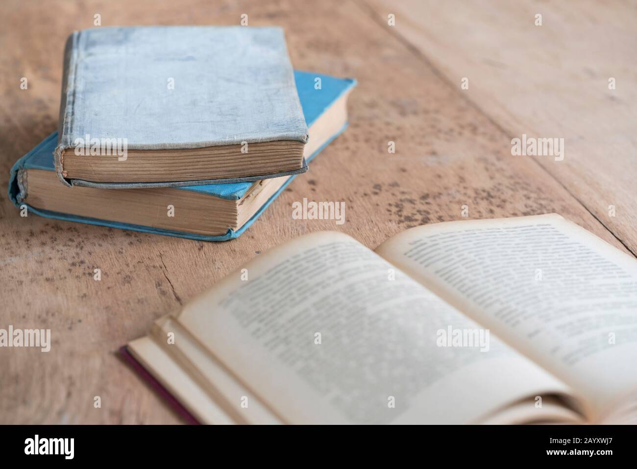 vecchi libri coperti di carta e uno aperto su un tavolo di legno con spazio di copia Foto Stock