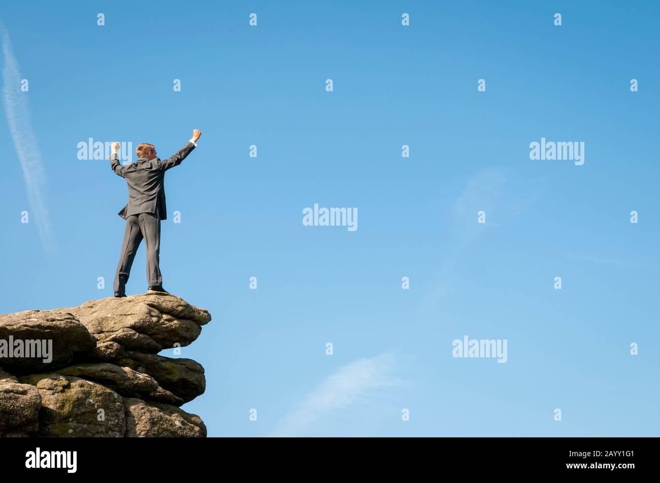 Imprenditore permanente sulla parte superiore di un lontano Rocky Mountain peak celebra nel cielo blu spazio copia Foto Stock