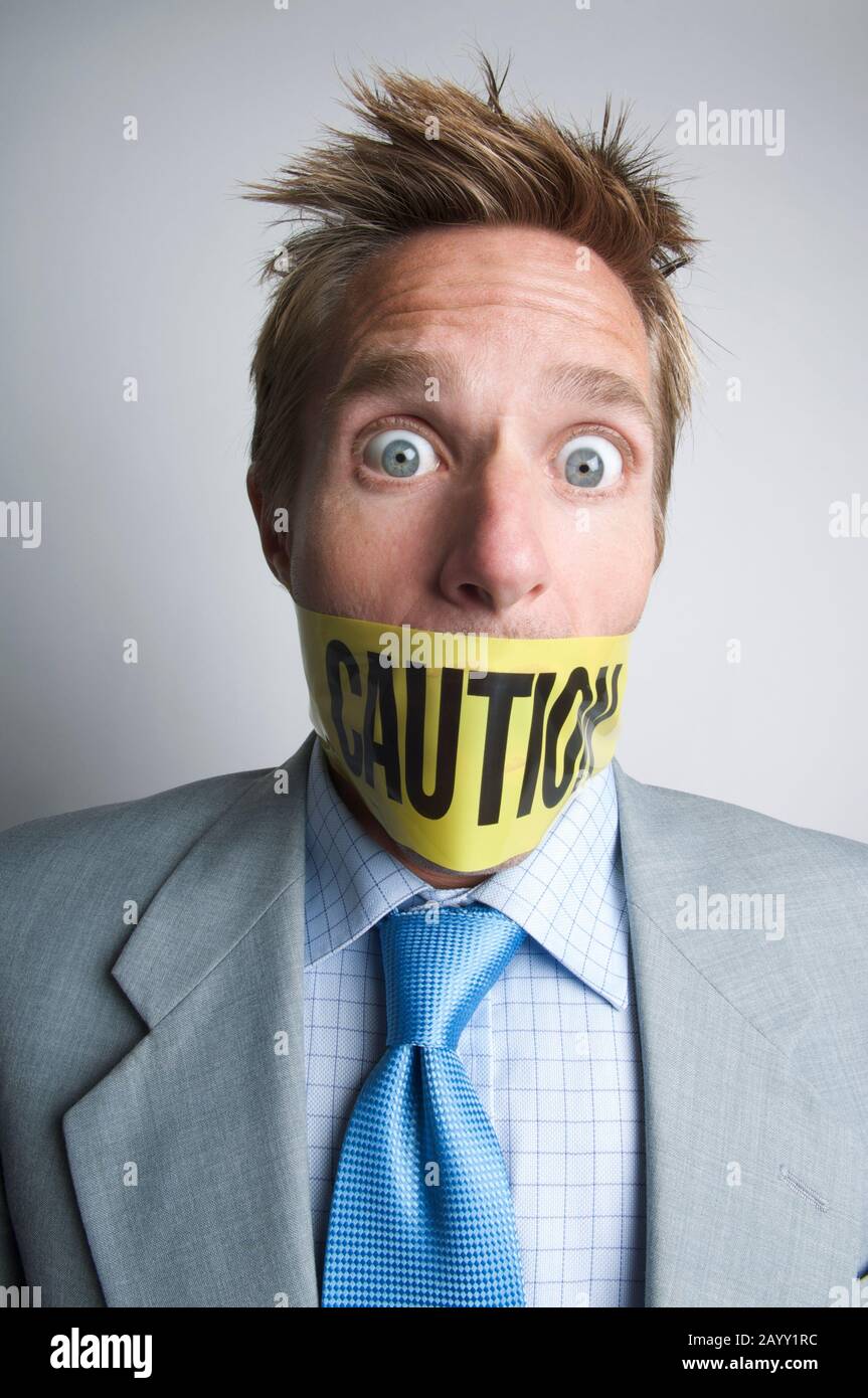 Businessman scioccato imbavagliato con nastro di cautela giallo Foto Stock