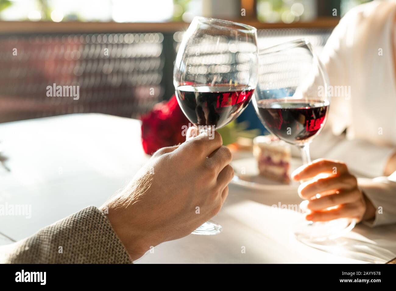 Primo piano orizzontale di uomo e donna irriconoscibile seduto in ristorante bicchieri reclinabili con vino rosso Foto Stock