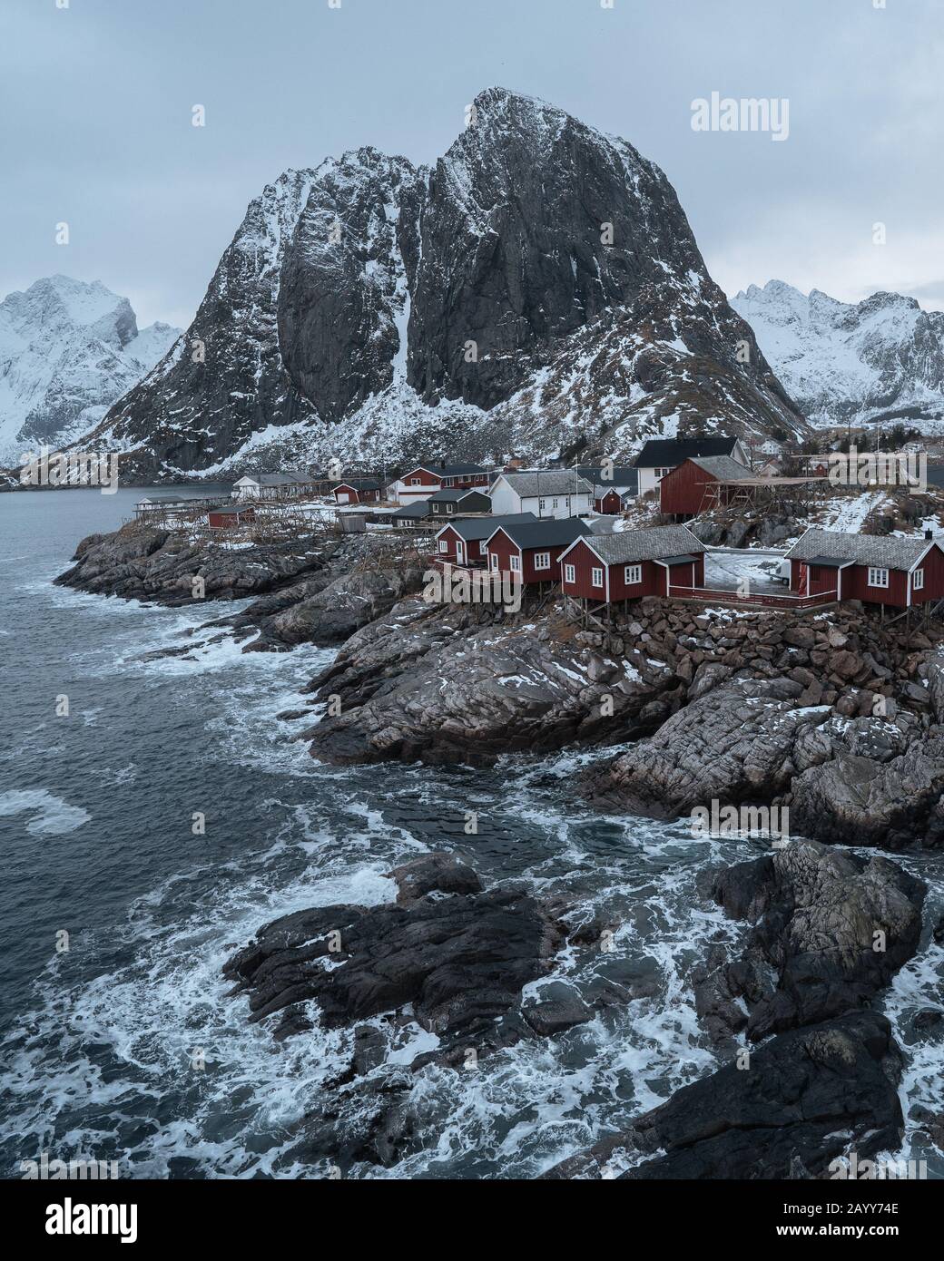Famosa attrazione turistica Hamnoy villaggio di pescatori sulle isole Lofoten, Norvegia. Tradizionali case a rorbuera rossa con neve in inverno al tramonto Foto Stock