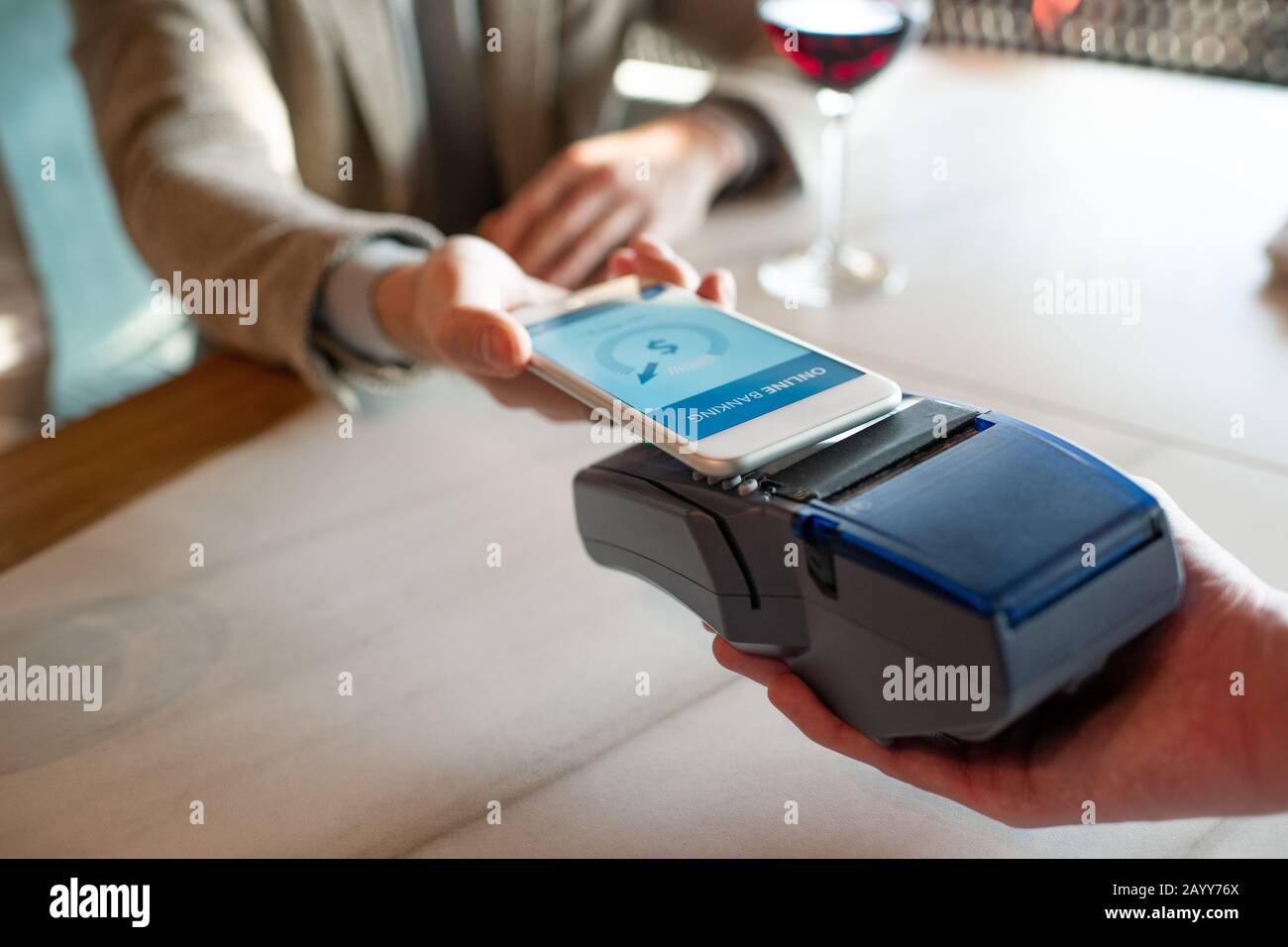 Angolo alto orizzontale primo piano di uomo irriconoscibile che paga per il pasto in ristorante utilizzando NFC sullo smartphone Foto Stock