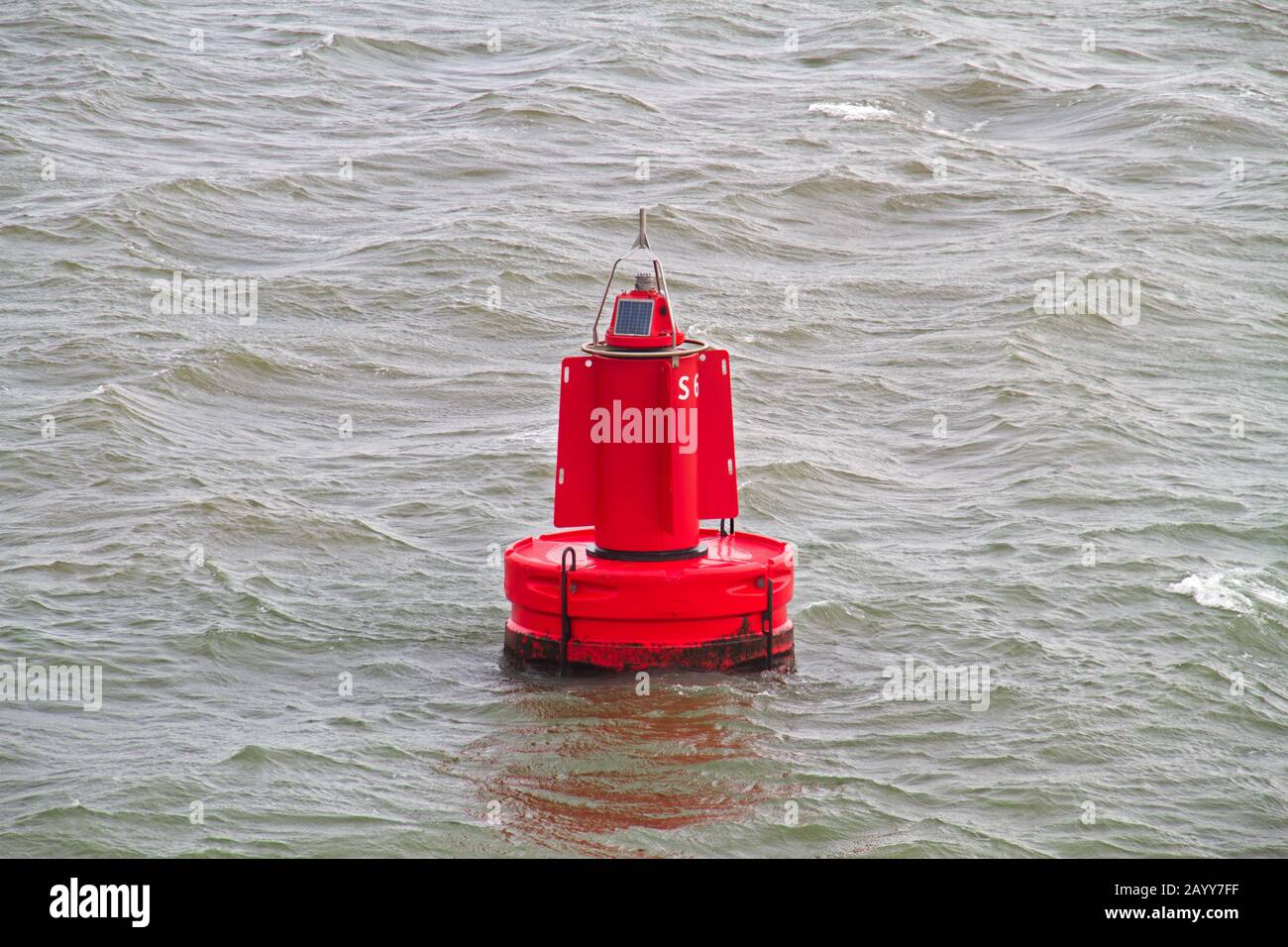 Una boa rossa galleggia sulla superficie grigia dell'acqua nel mare olandese di Wadden Foto Stock