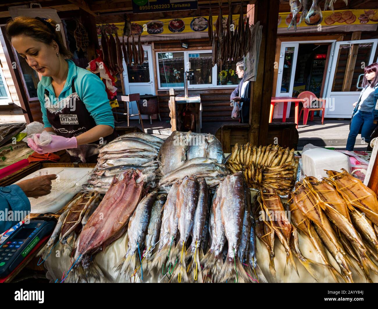 Donna che vende pesce secco e affumicato in vendita presso lo stallo del mercato, Listvyanka, Irkutsk Region, Siberia, Russia Foto Stock