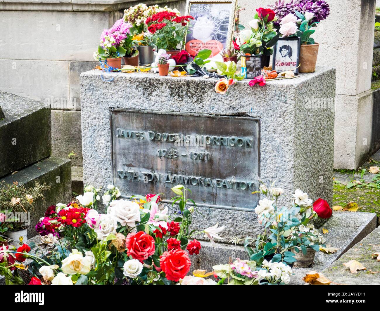 Primo piano della lapide di Jim Morrison ricoperta di fiori tra le altre tombe nel cimitero monumentale di Pere Lachaise, Parigi Foto Stock