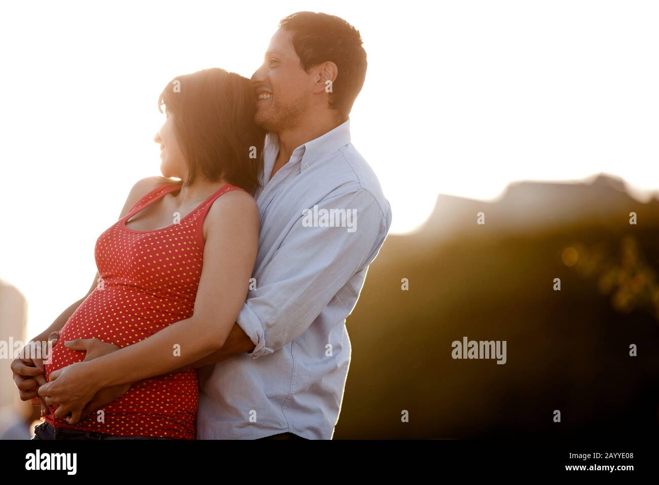 Venti-Qualcosa l'uomo abbraccia la sua moglie incinta. Foto Stock