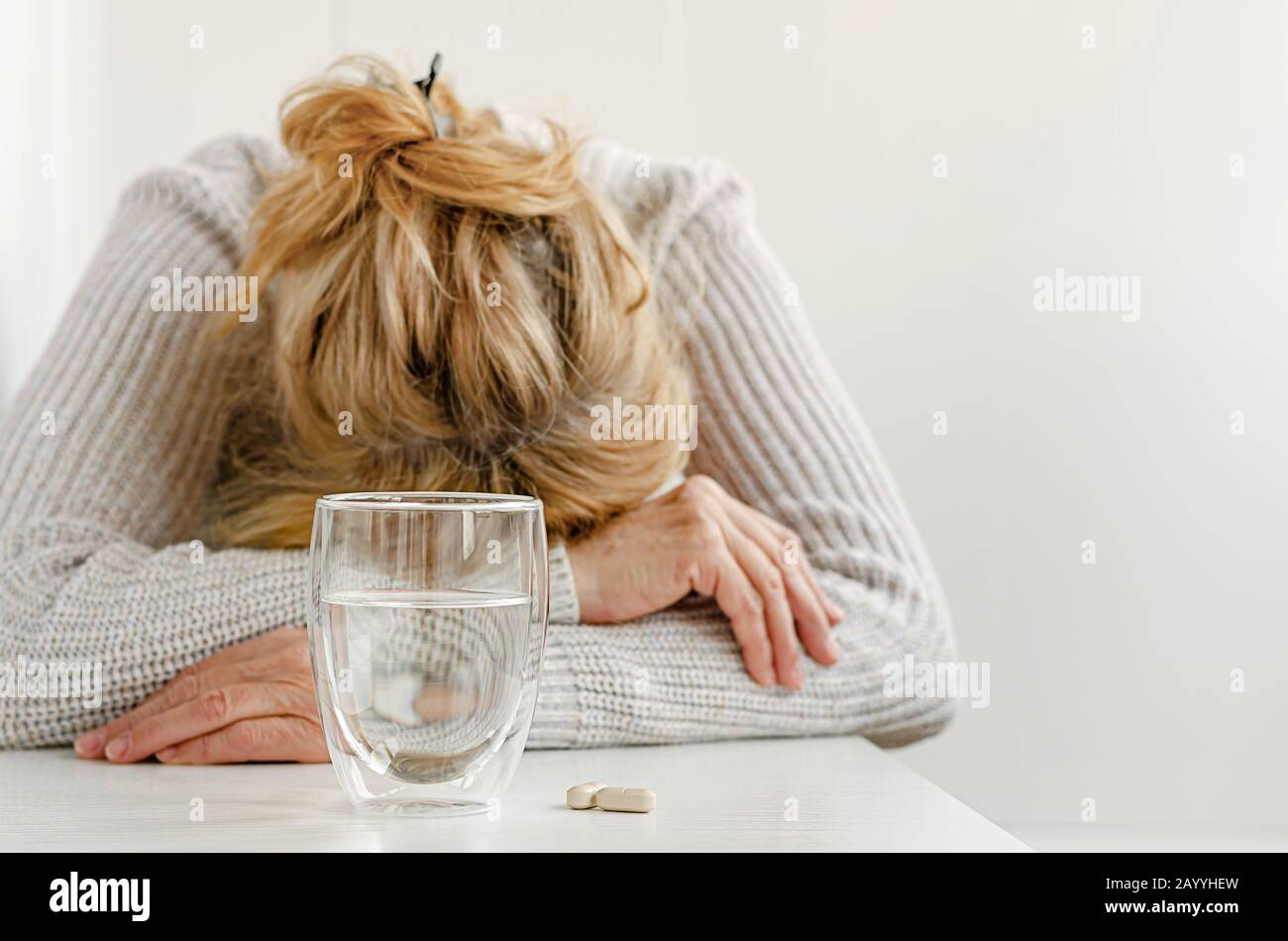 Donna anziana sentirsi stressato. Fuoco selettivo su vetro e pillole. Concetto di trattamento della depressione Foto Stock
