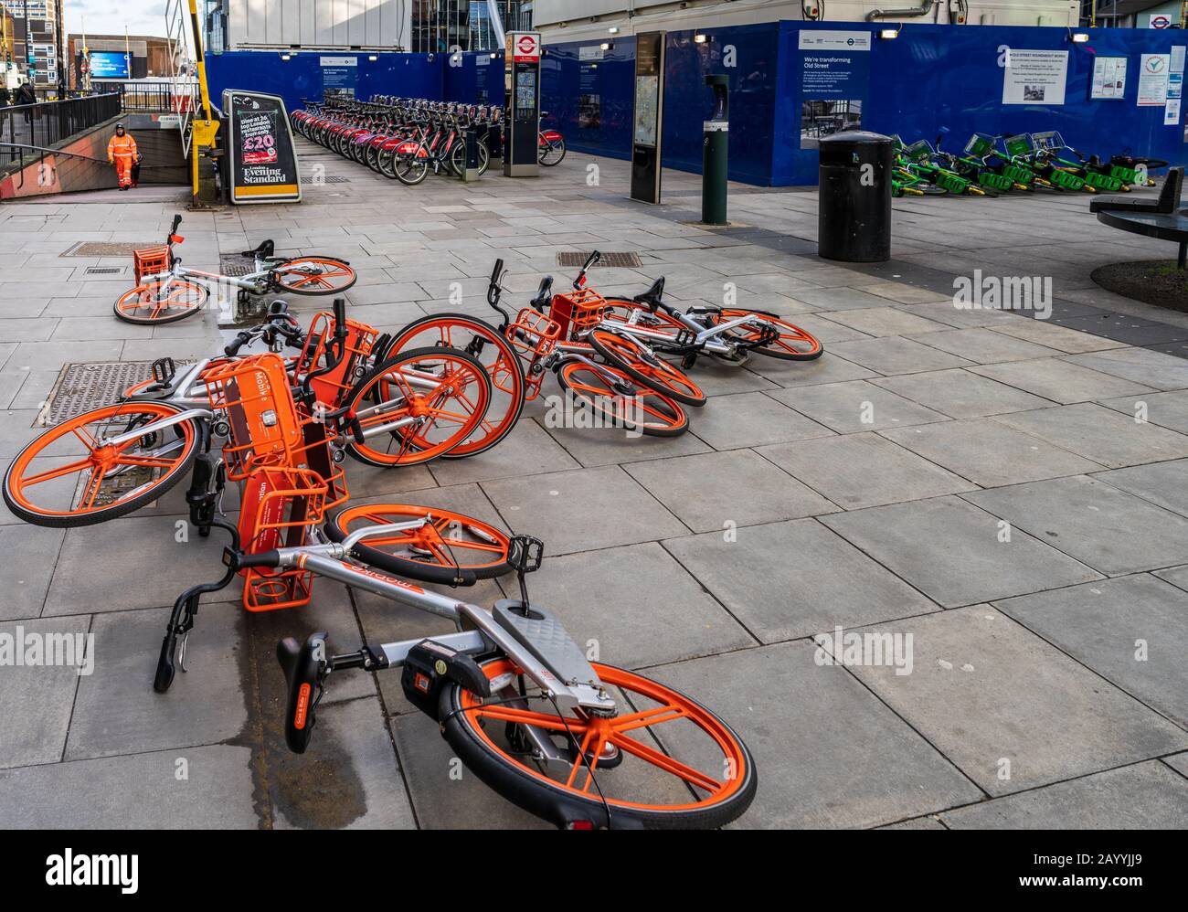 Noleggio Di Dockless In Bicicletta A Londra. Uno svantaggio delle bici dockless di noleggio è la loro vulnerabilità ai venti alti quando parcheggiati sulla strada. Moto ormeggiate dietro. Foto Stock